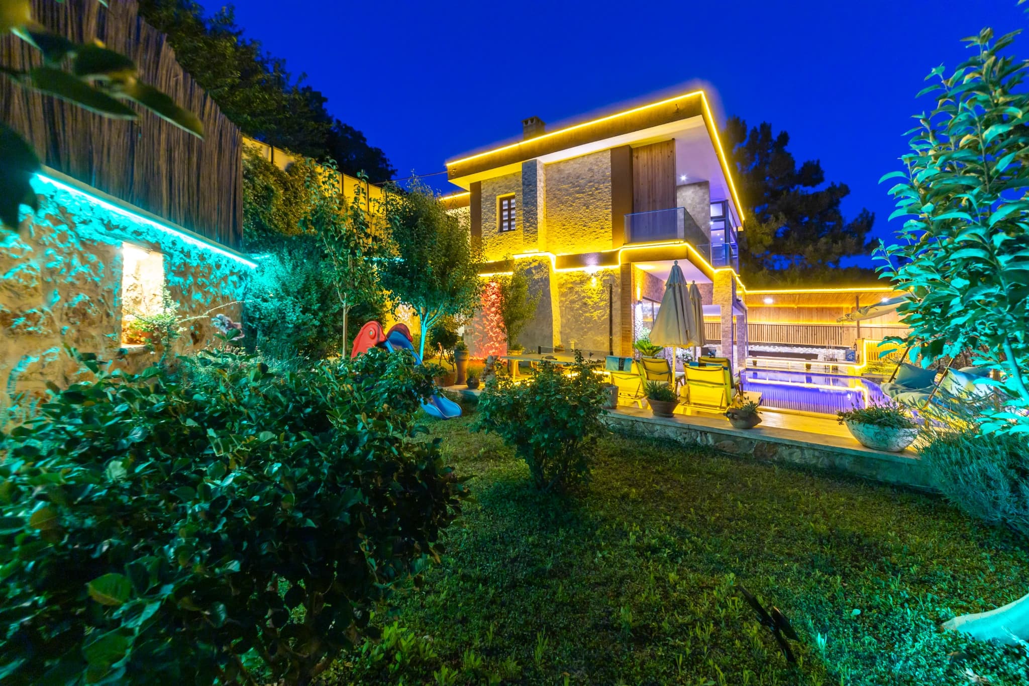 Beautifully lit garden pathway connecting villa structures with ambient lighting.