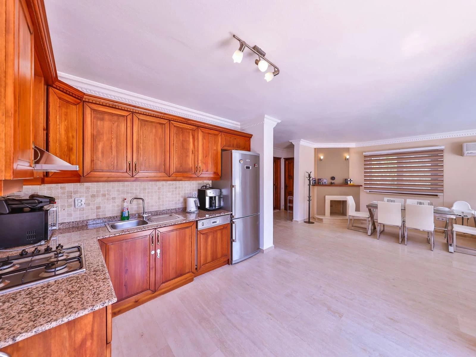 Spacious kitchen with wooden cabinetry, stainless steel appliances, and open layout to dining area.