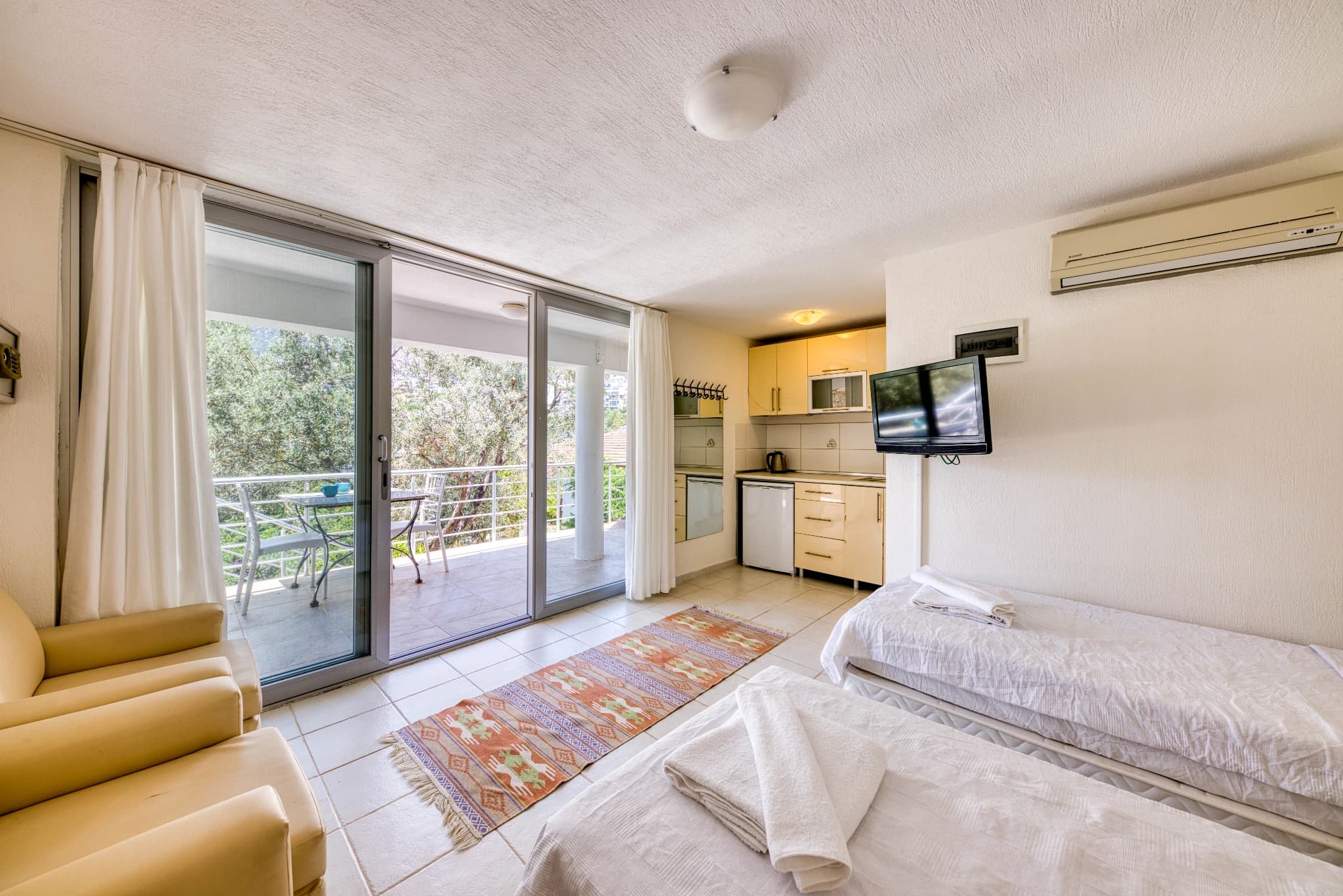 Studio bedroom with balcony access, integrated kitchen, and modern furnishings.