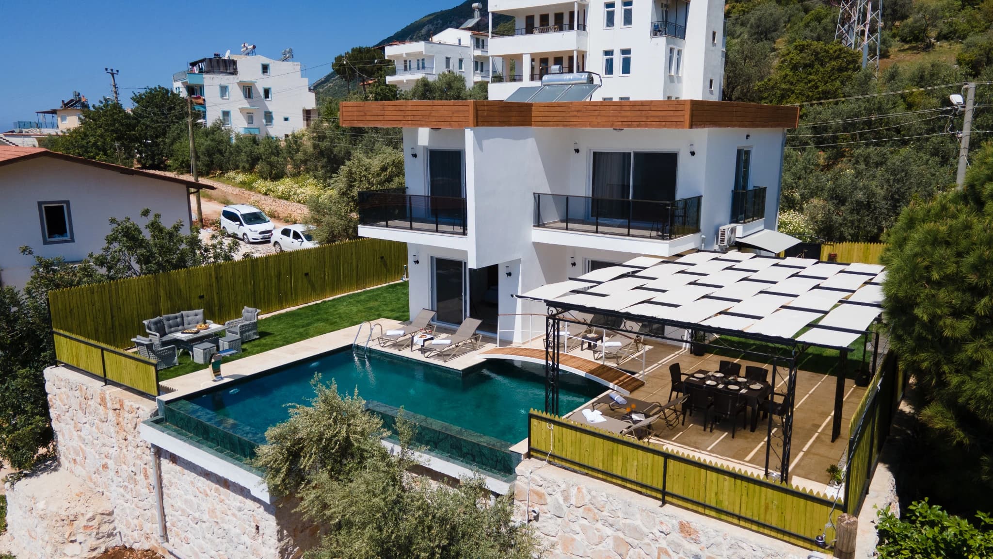 Full property overview showing pool area with sun loungers and shaded outdoor dining space.