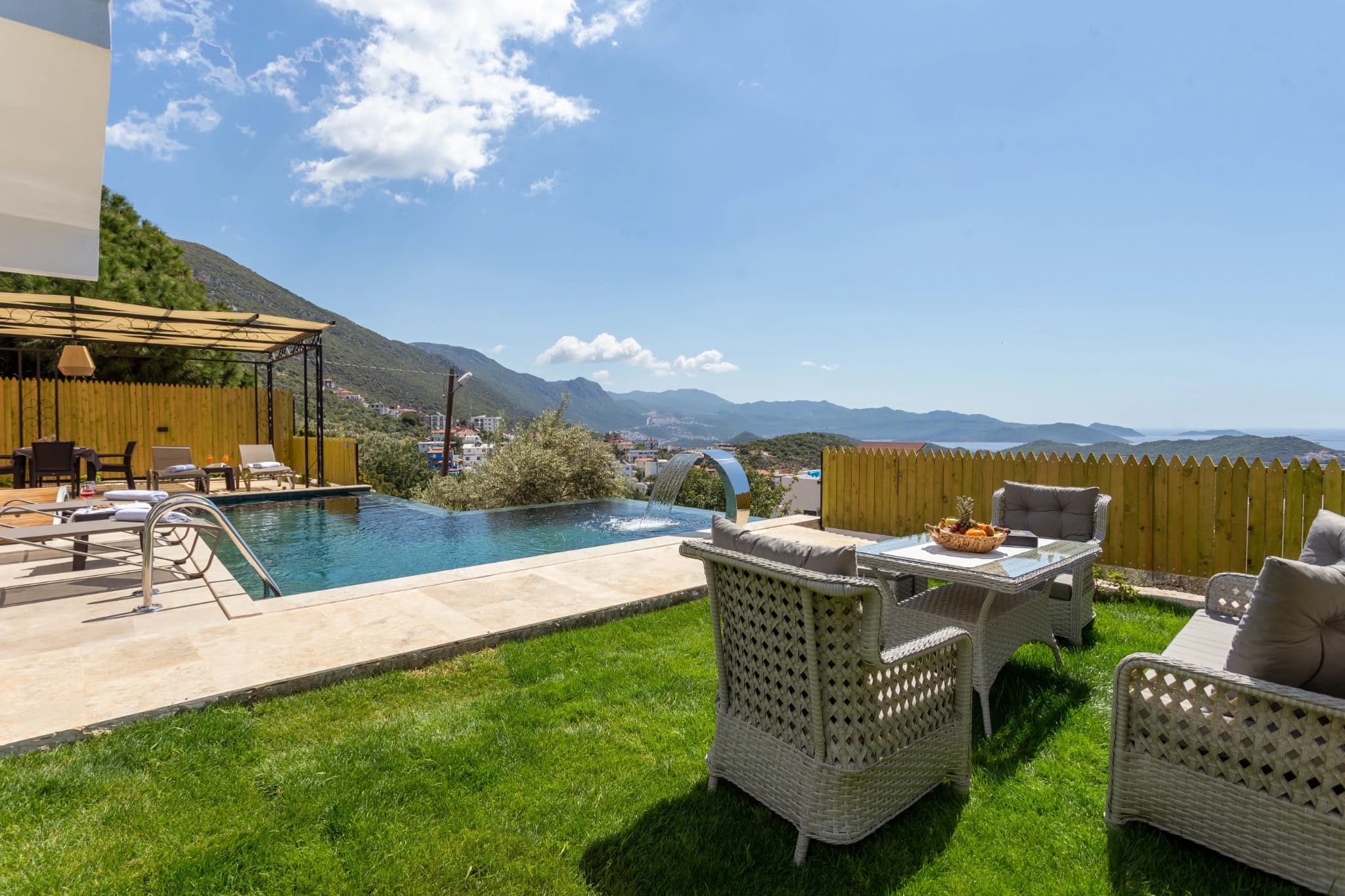 Stunning infinity pool with mountain and sea views, outdoor seating, and manicured gardens.