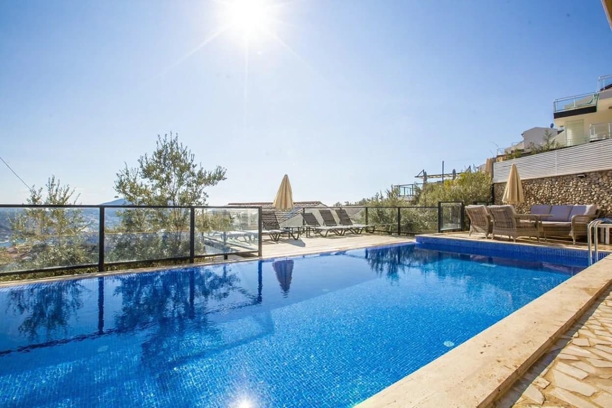Crystal-clear pool with scenic valley and coastal views from elevated terrace.