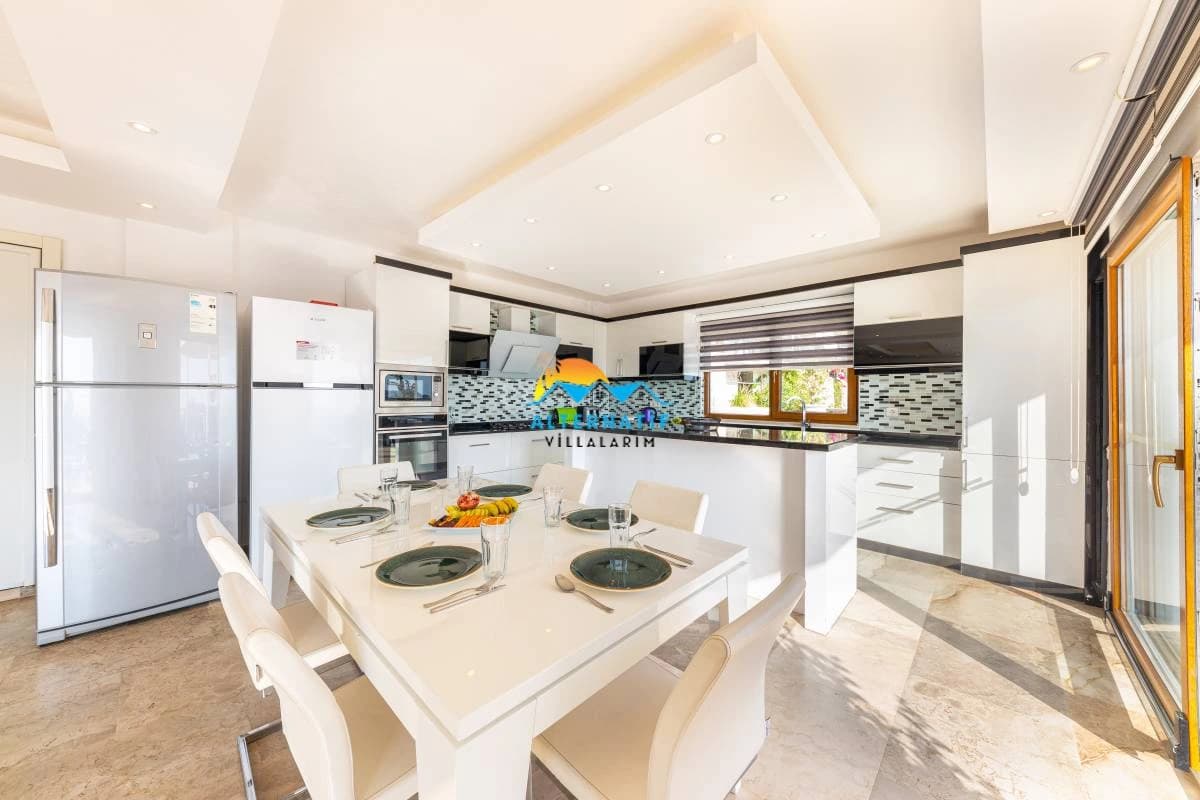 Modern open kitchen with sleek white finishes, central island, professional appliances, and integrated dining for entertaining.