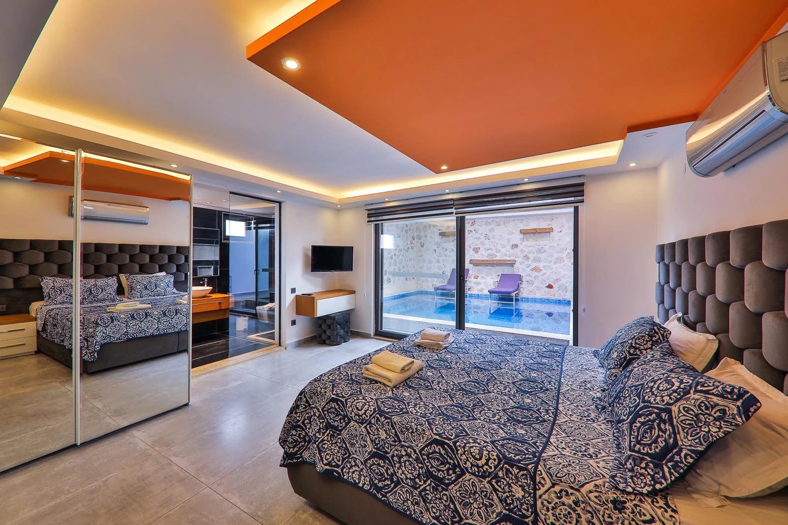 Luxurious master bedroom with a double bed, ensuite bathroom access, and private pool views through sliding glass doors.