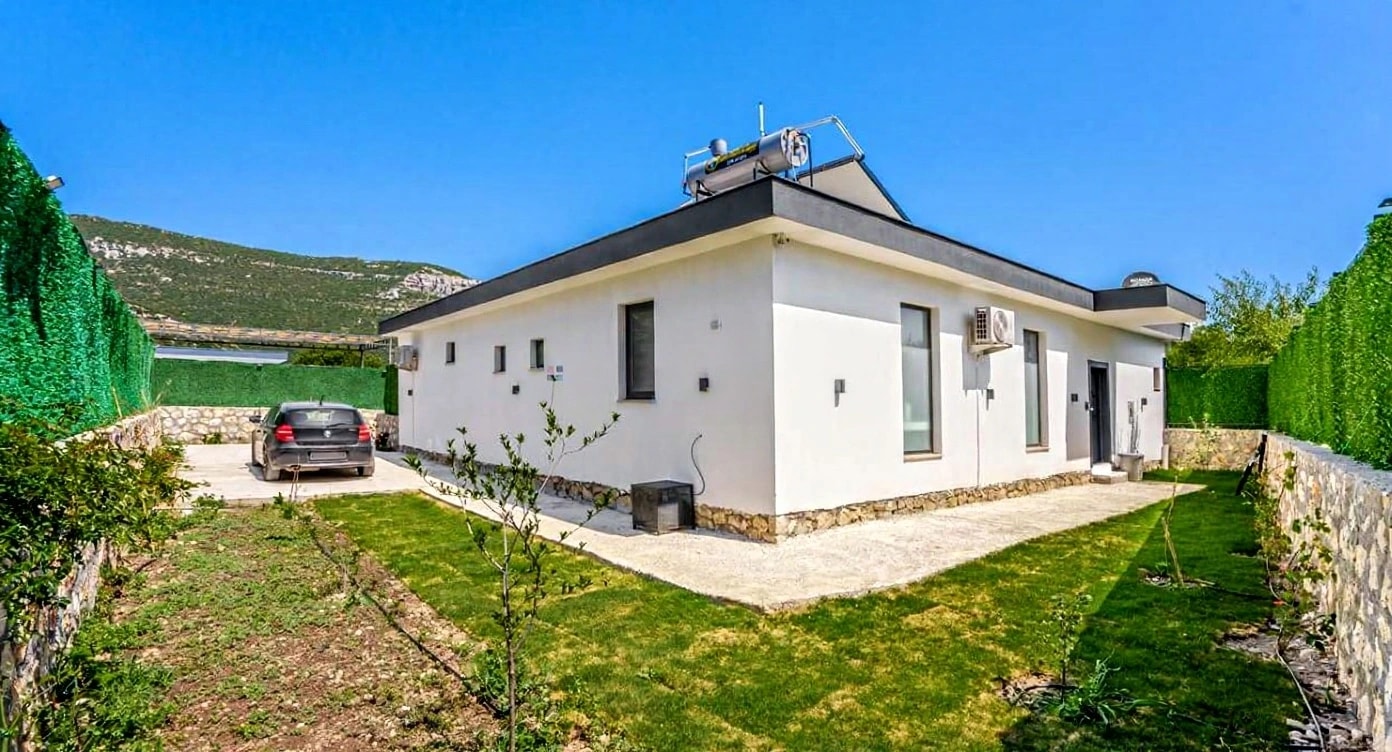 Modern white villa exterior with private parking and lush landscaped grounds.