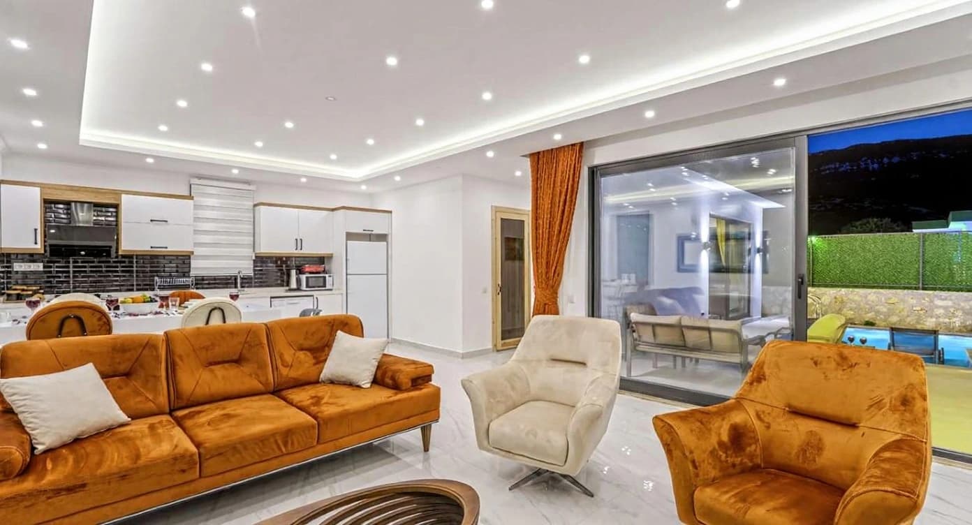 Spacious living room with comfortable seating and seamless transition to pool terrace through glass doors.