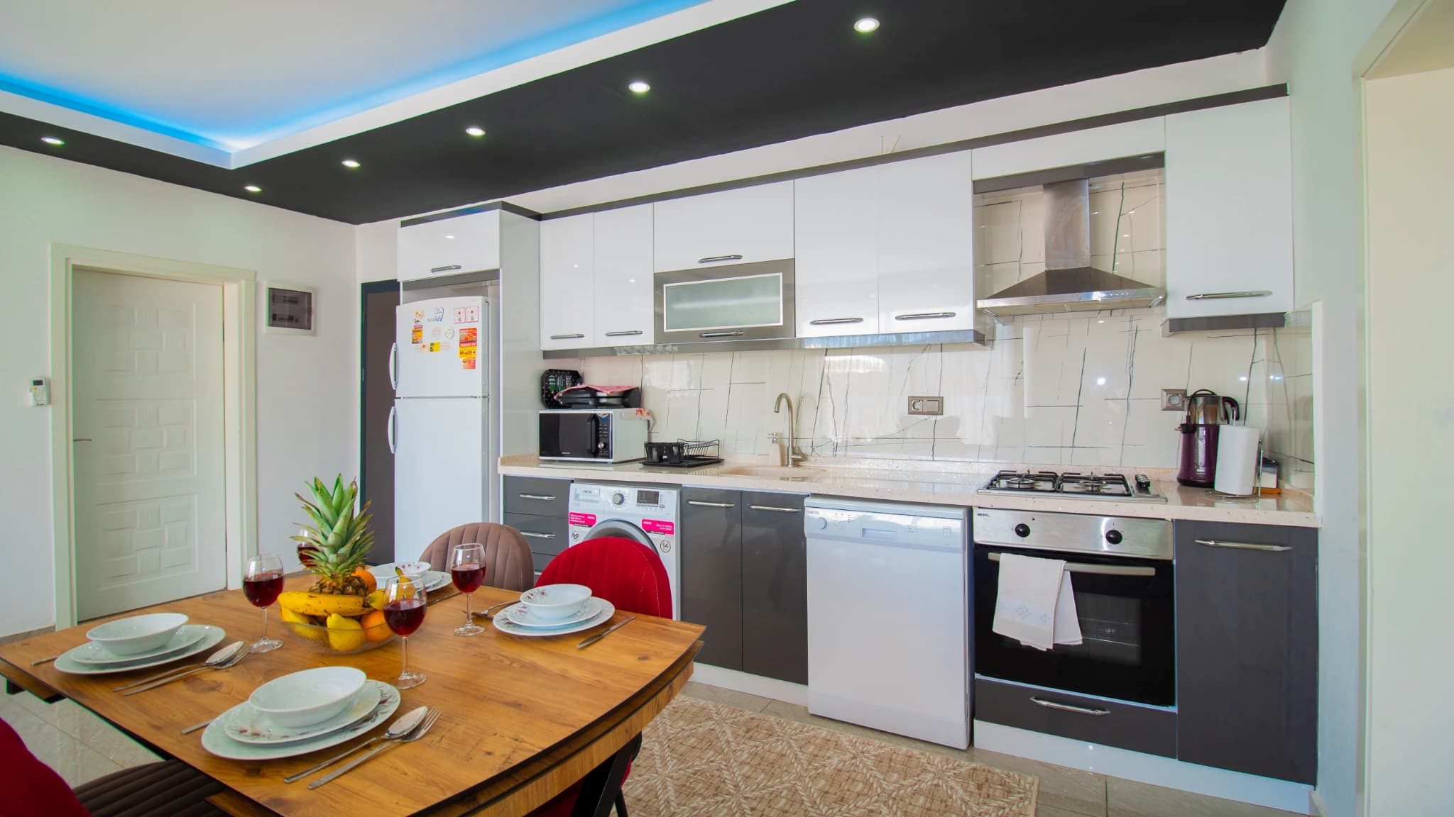 Fully equipped kitchen with dining table, modern appliances, and fresh produce display.