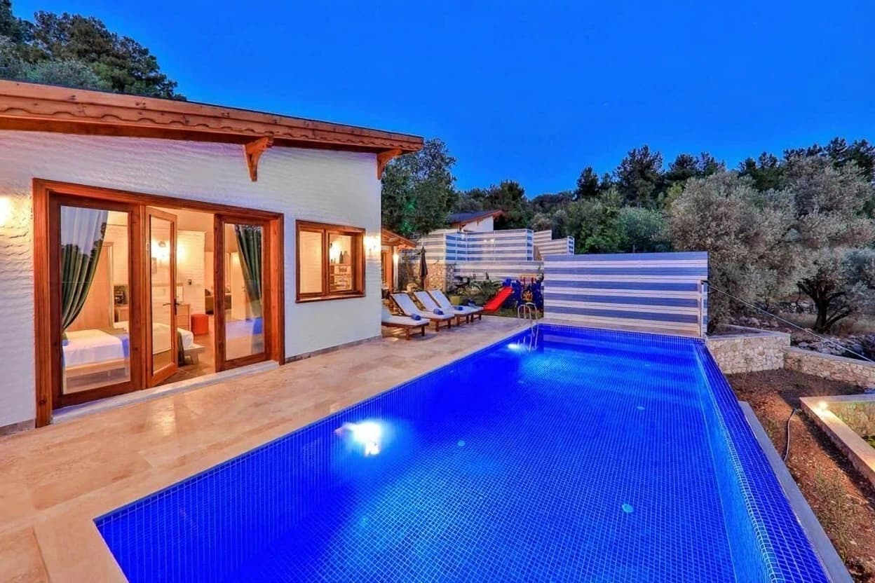 Modern private pool with lounge chairs and privacy fencing alongside the villa.