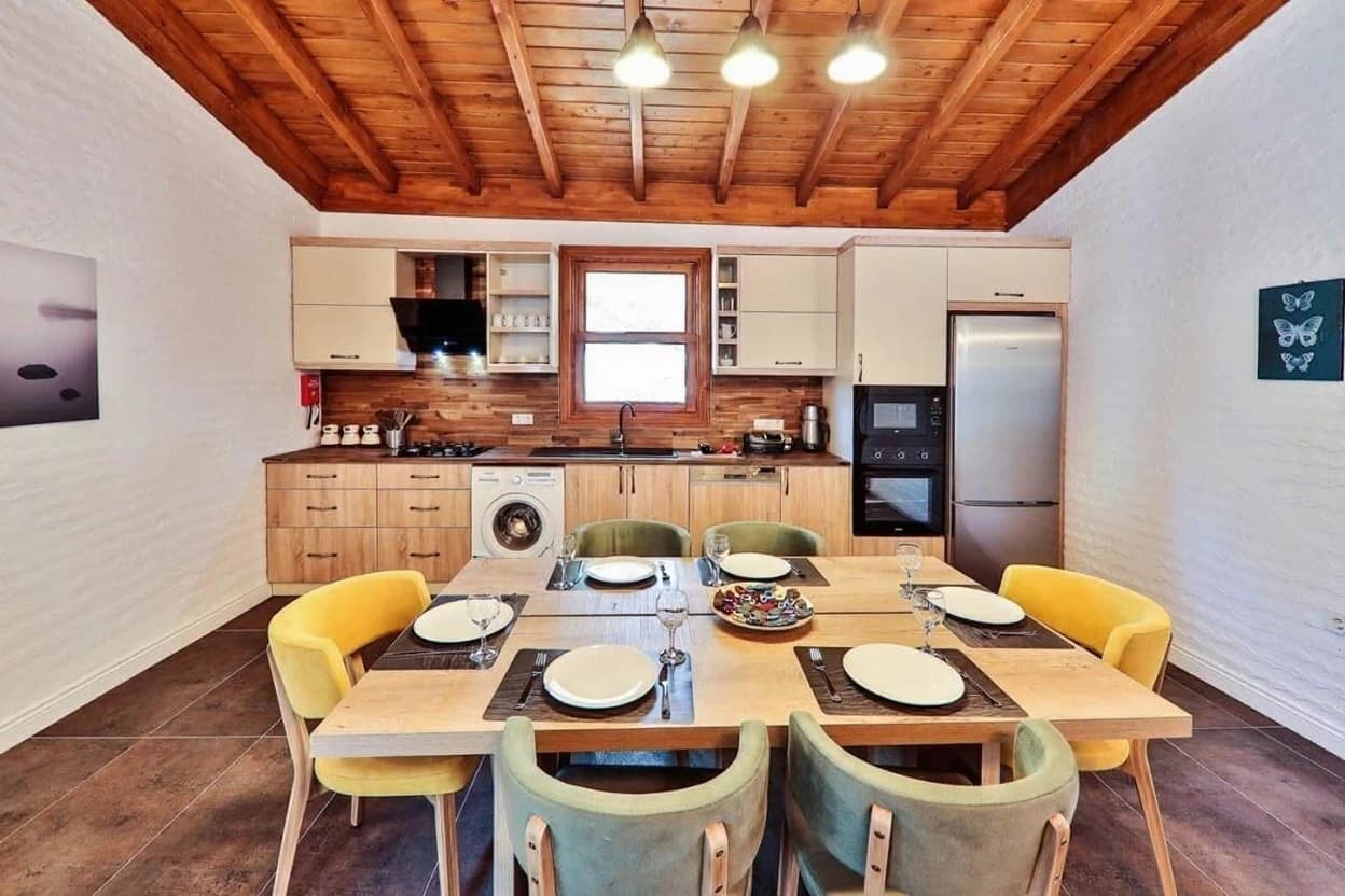 Modern dining kitchen with wooden beamed ceiling, fully-equipped kitchen, and dining seating for six.