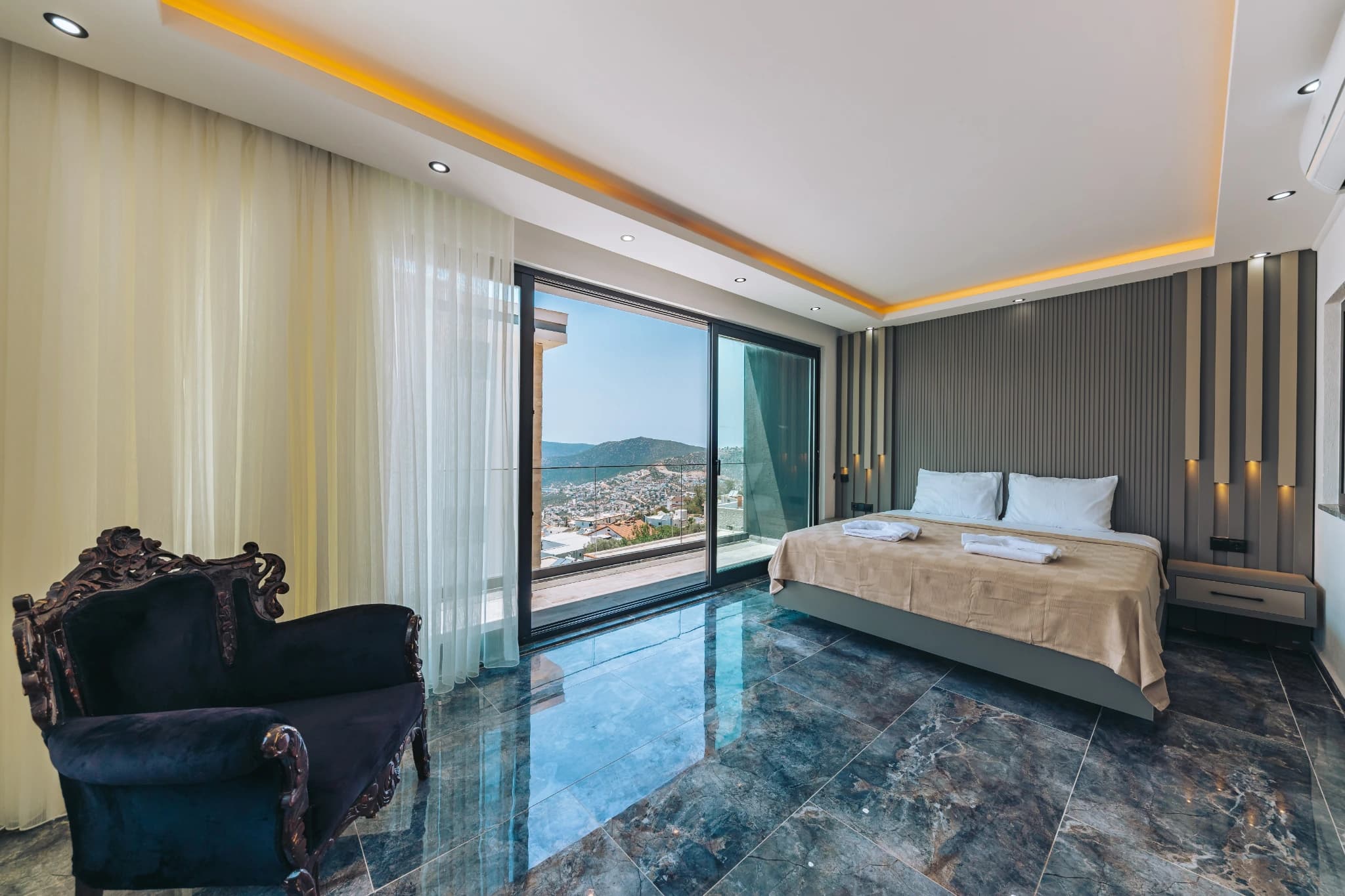 Luxurious master bedroom with panoramic sea and mountain views from private balcony.