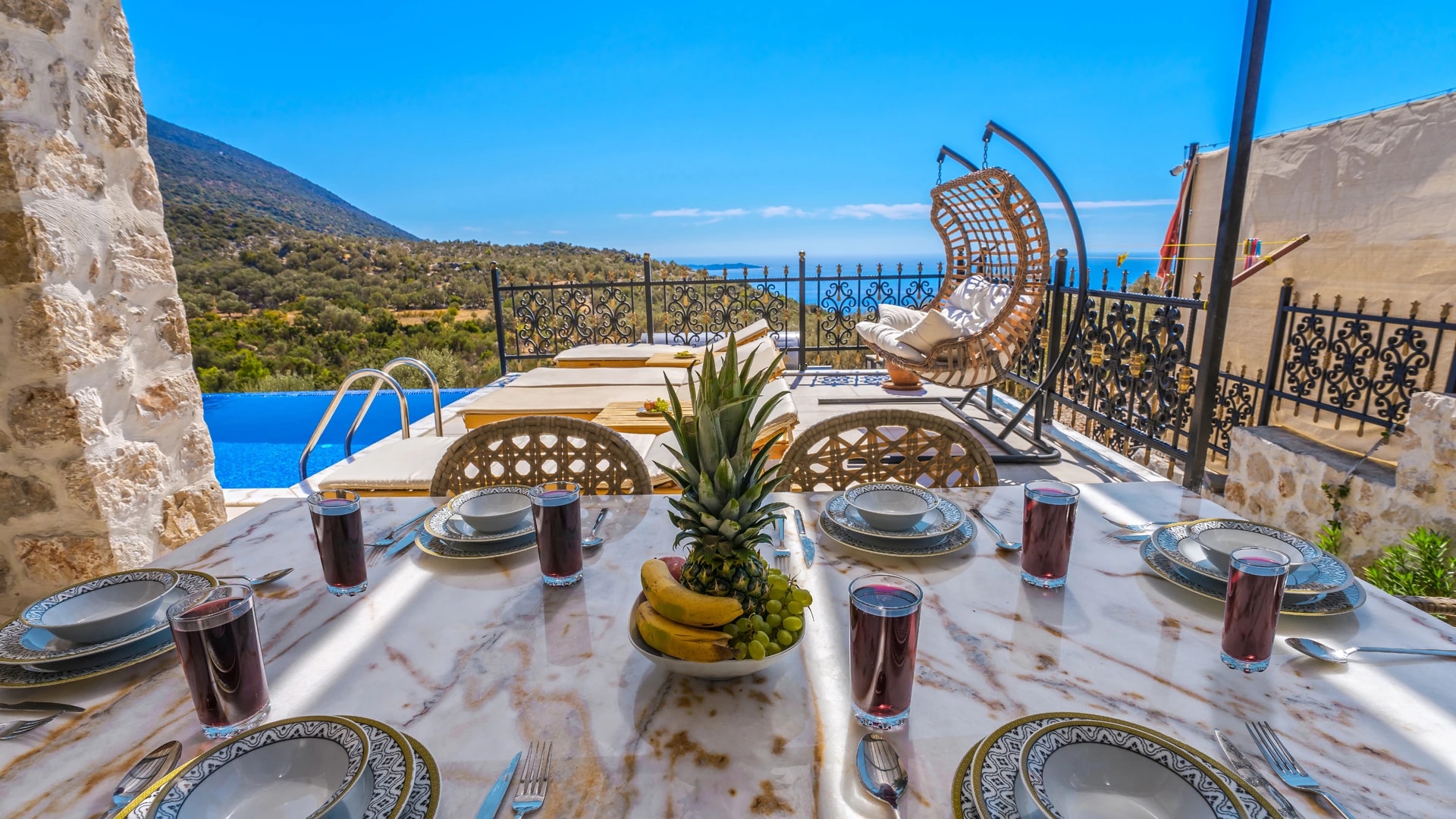 Elegant outdoor dining table set with sea and mountain vistas.