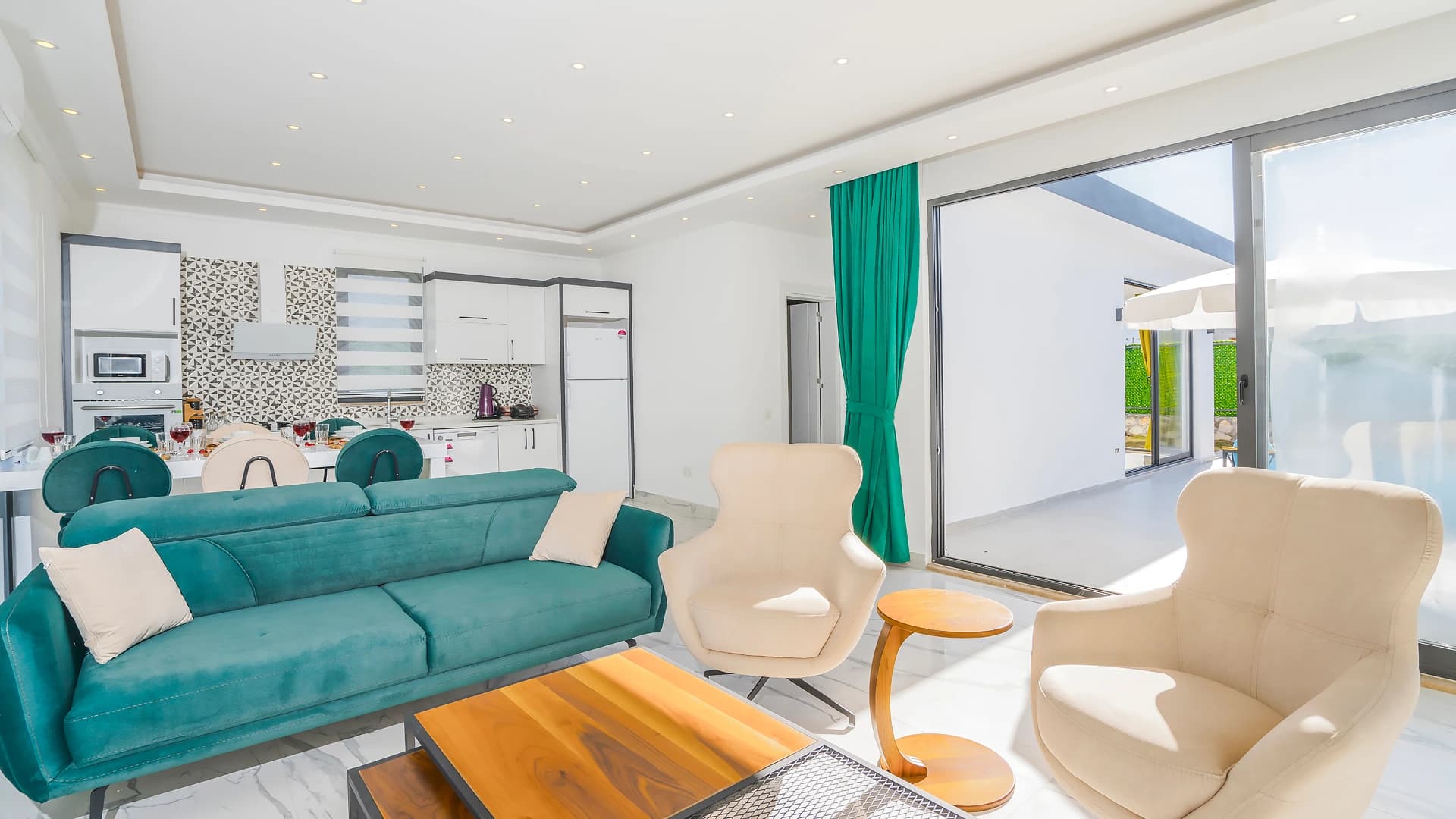 Contemporary living space with turquoise velvet sofa, designer armchairs, and direct garden access.