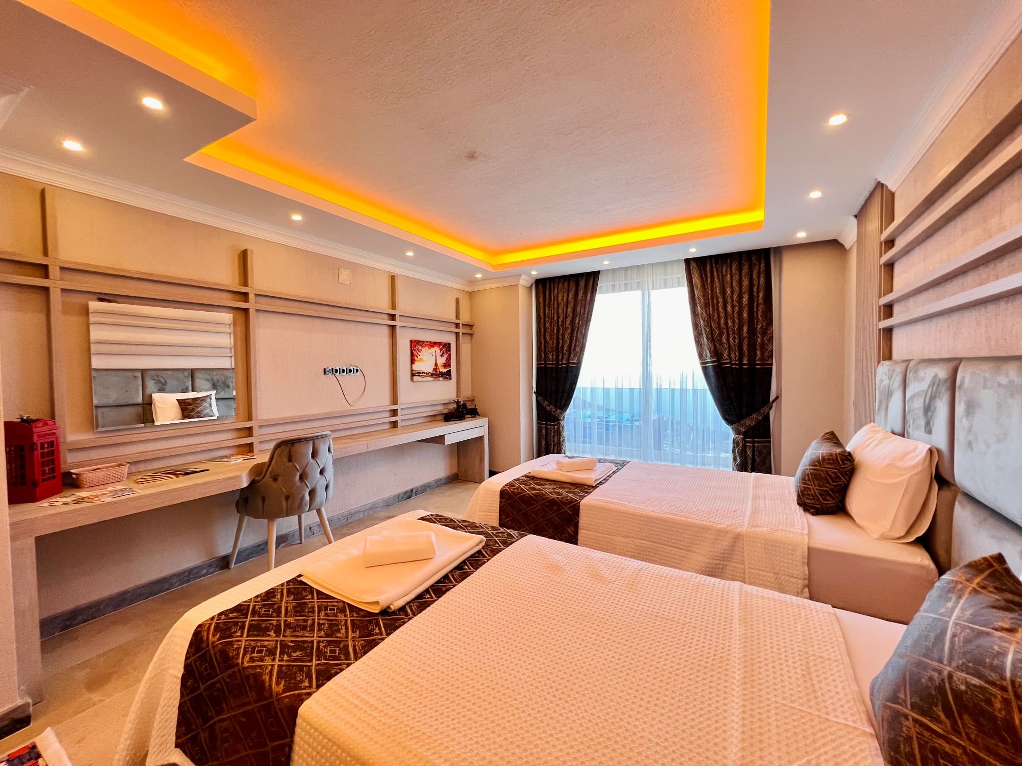 Spacious twin bedroom with elegant furnishings, ambient ceiling lighting, and balcony access.