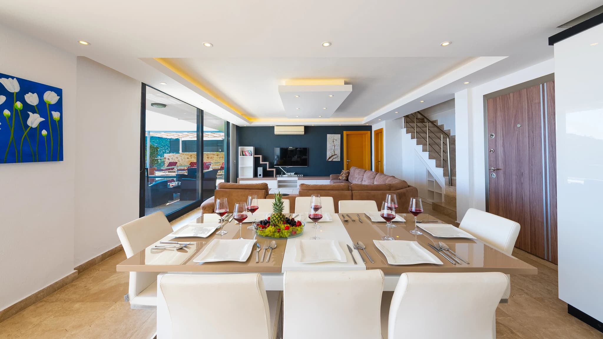 Sophisticated dining area with panoramic sea views through glass doors, overlooking terrace and pool.