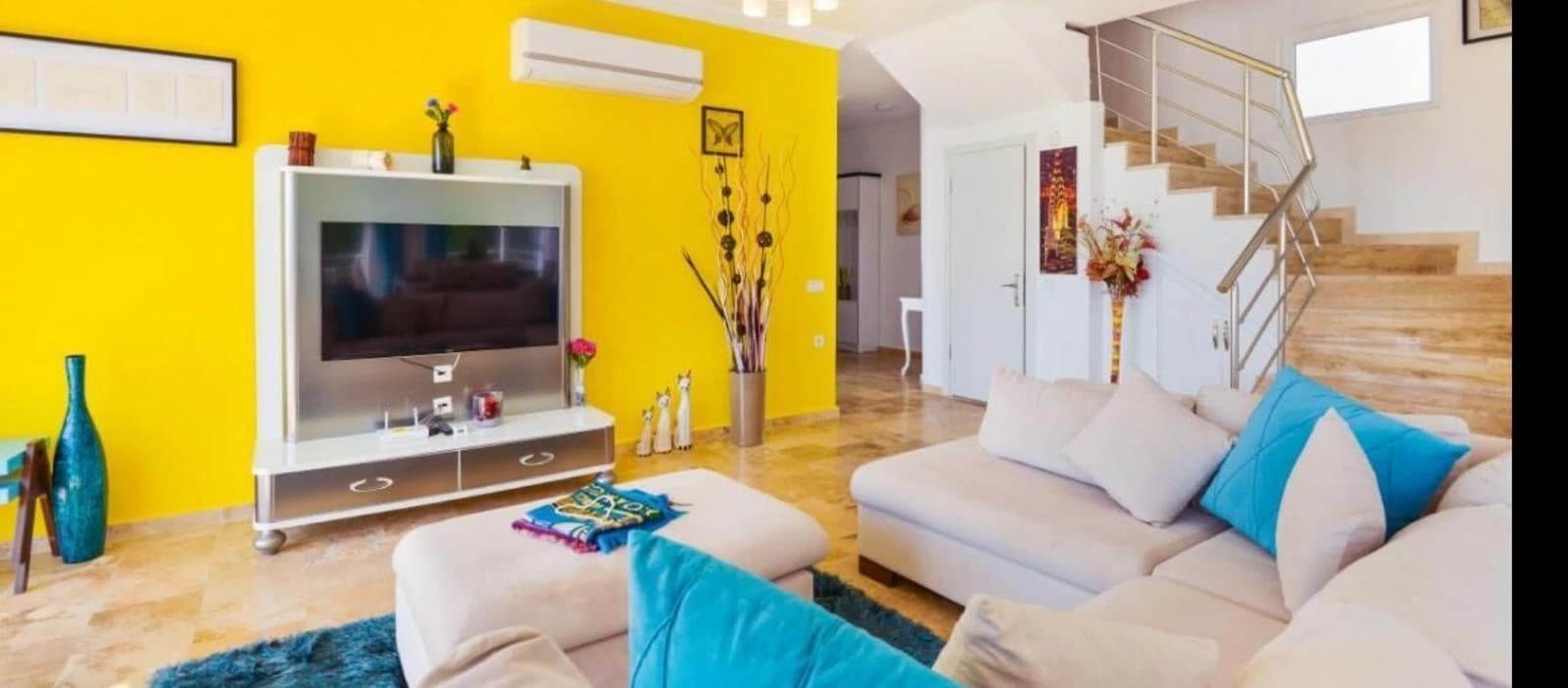 Vibrant modern living room with bold yellow feature wall, comfortable seating, and entertainment center.
