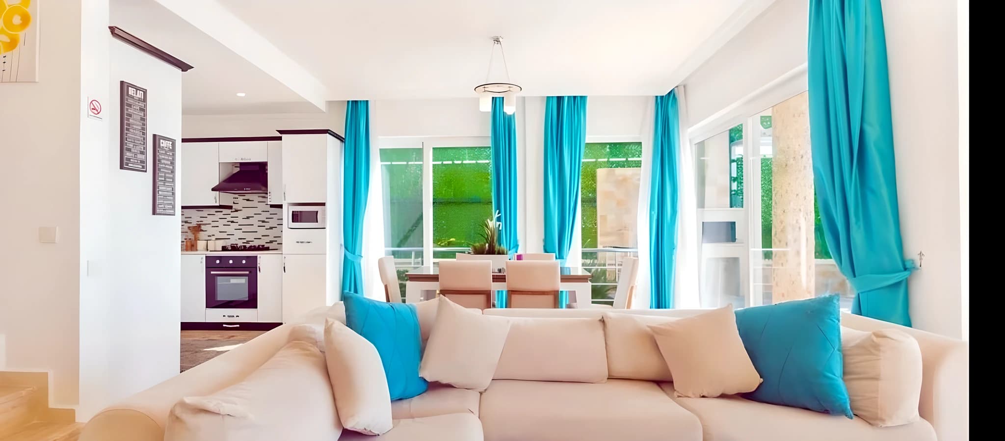 Open-plan living and dining area with plush seating, integrated kitchen, and scenic garden views.