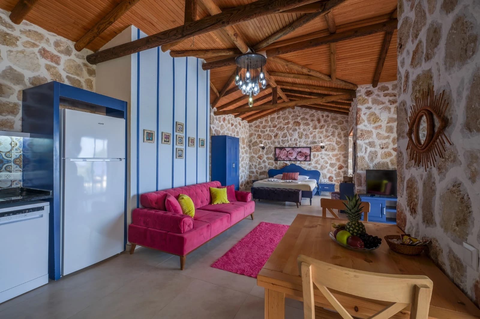 Spacious open-plan bedroom with double bed, integrated living area, and rustic wooden beams.