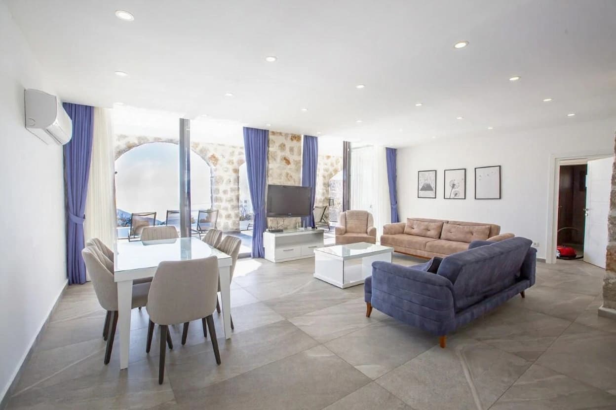 Spacious open-plan living area with sofas, fireplace, and sea views.