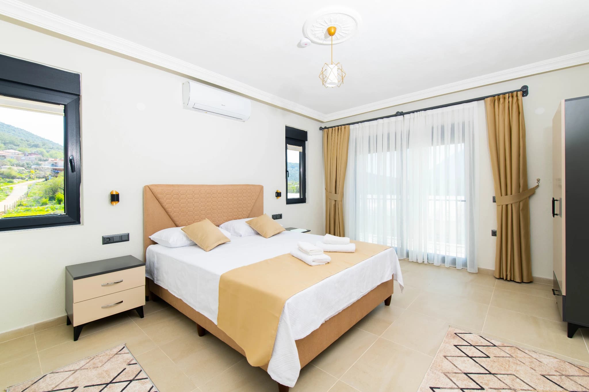 Bright master bedroom with queen bed, mountain views, and direct balcony access.
