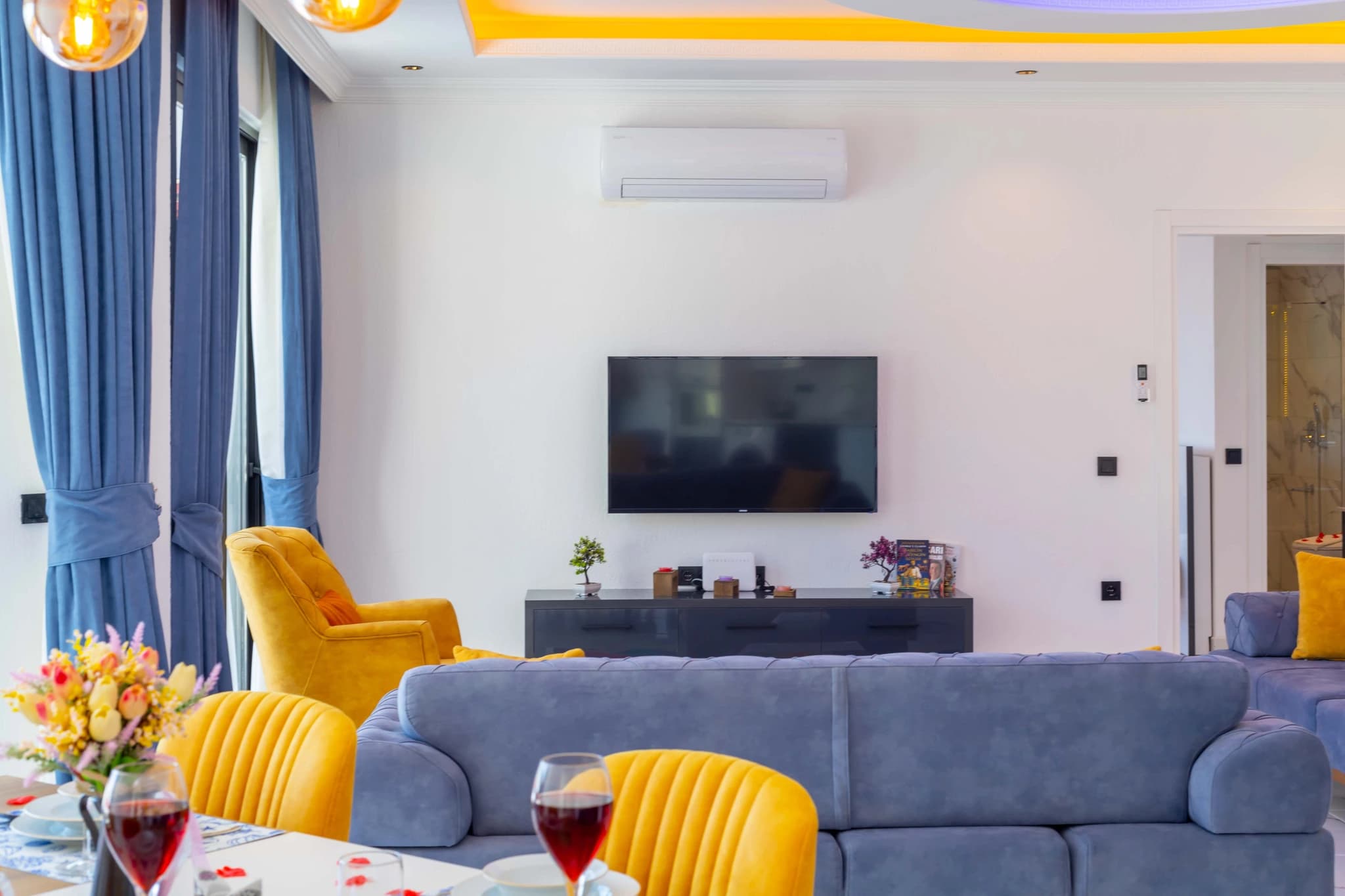 Secluded Garden Villa with Private Pool and Mountain Views in Kalkan – Spacious living area with comfortable seating, entertainment system, and elegant yellow and blue color scheme.