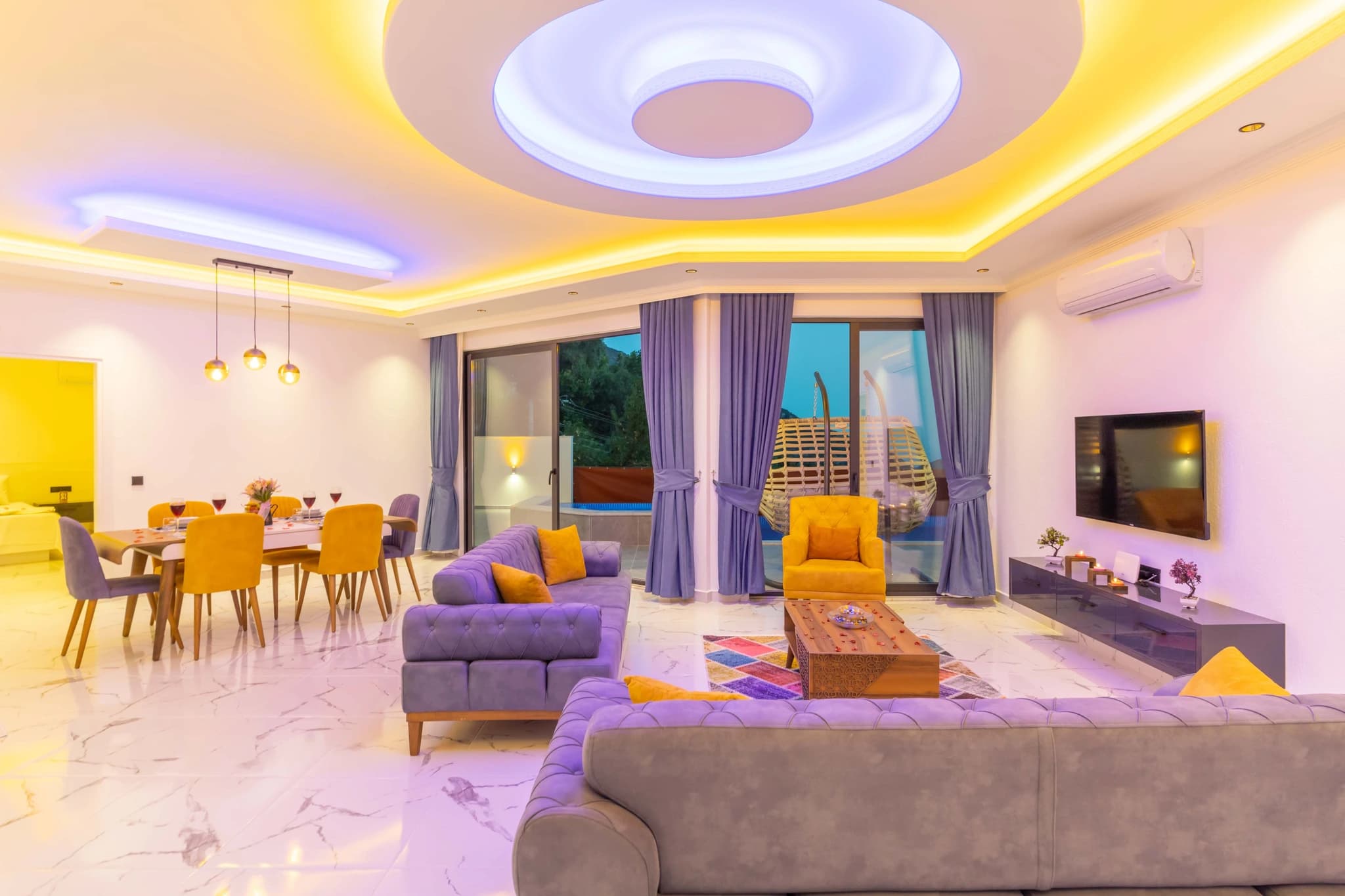 Secluded Garden Villa with Private Pool and Mountain Views in Kalkan – Open-plan living room with modern purple sofas, accent lighting, and nature views terrace access.