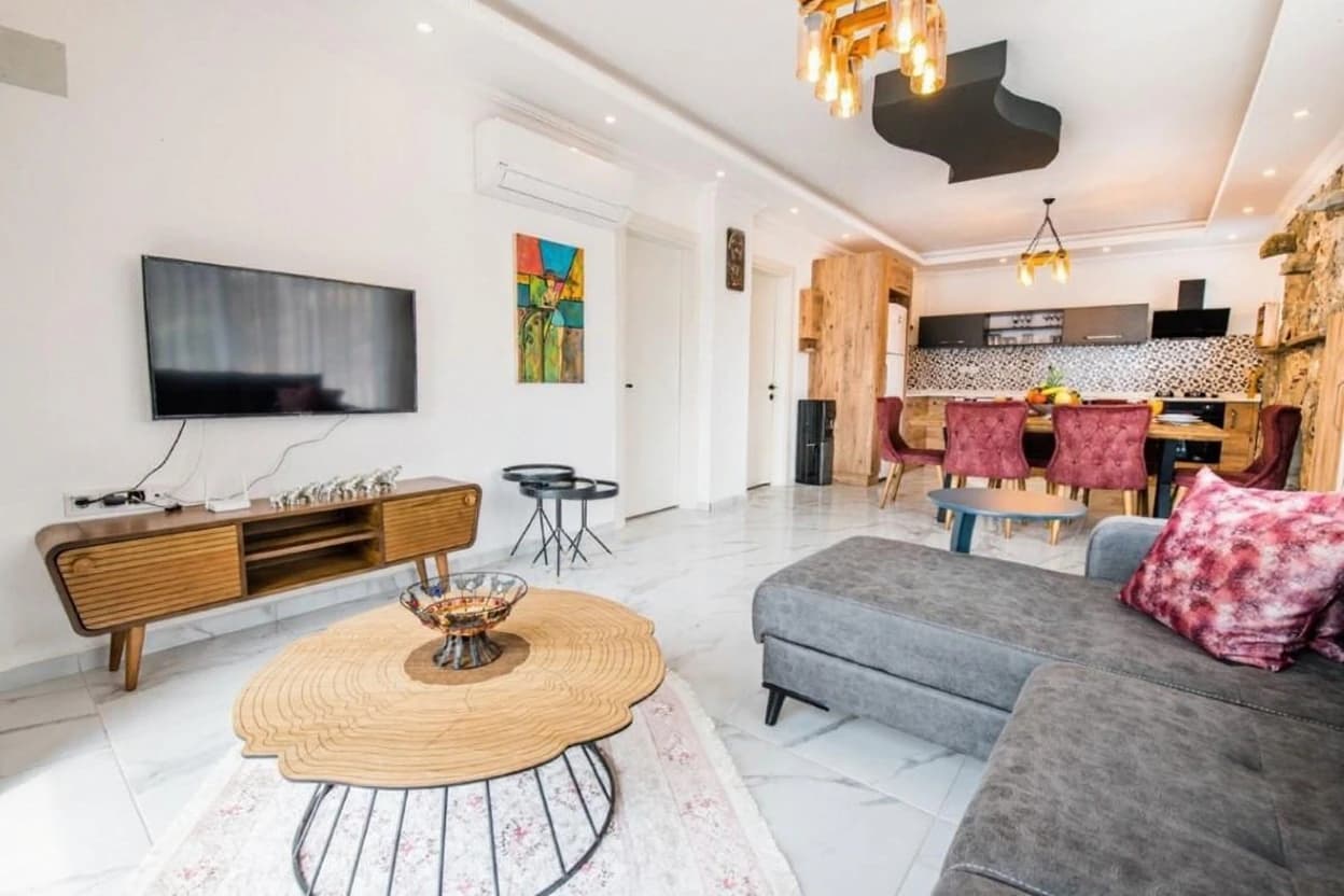 Spacious open-plan living room with contemporary furnishings and integrated kitchen in background.