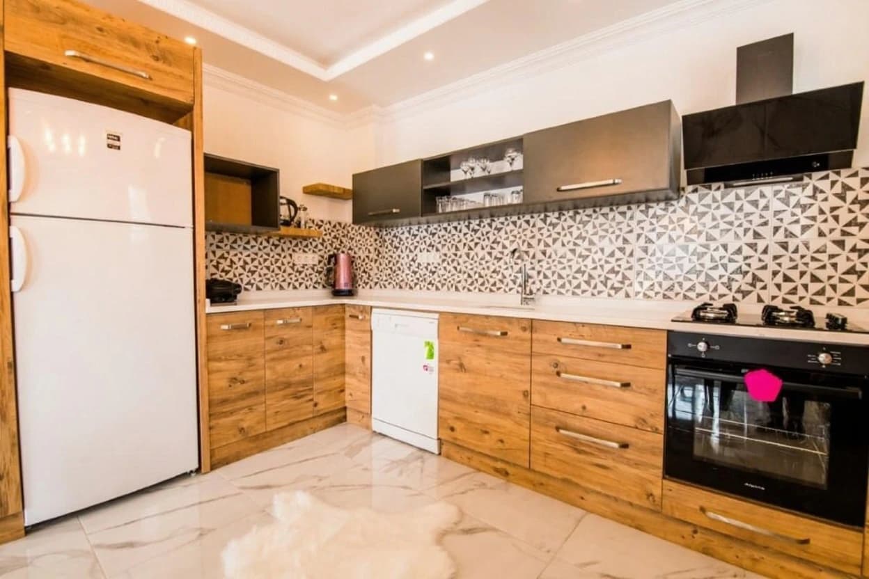 Fully equipped kitchen with wooden cabinetry and decorative patterned backsplash.