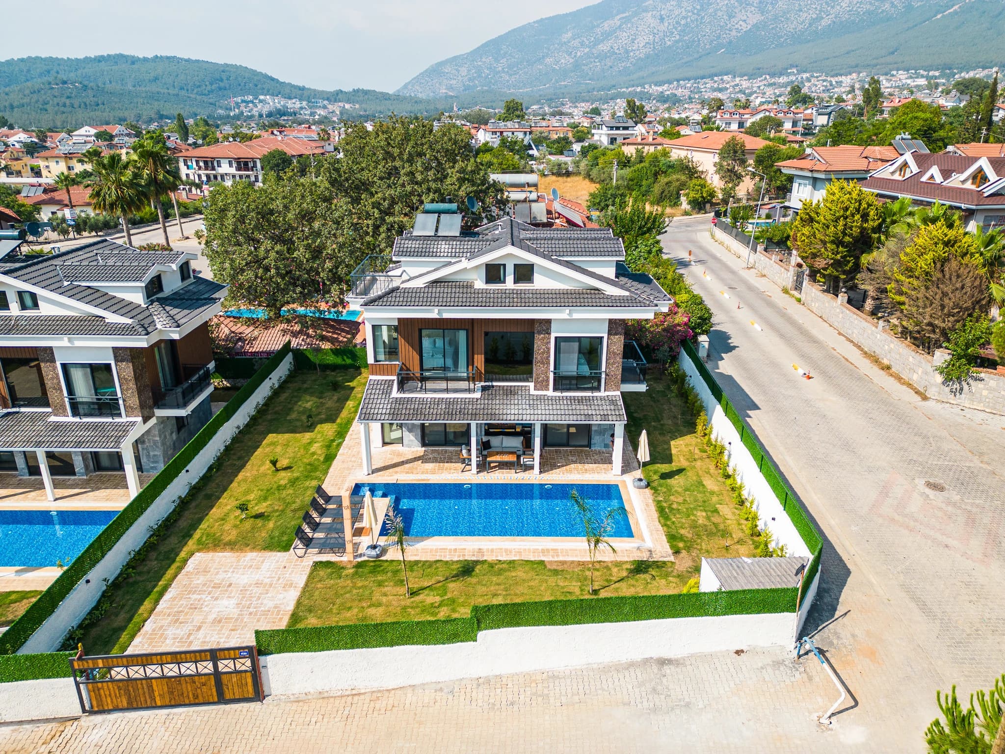 Direct overhead shot of villa showing private pool, patio area, landscaped garden, and scenic mountain vista.