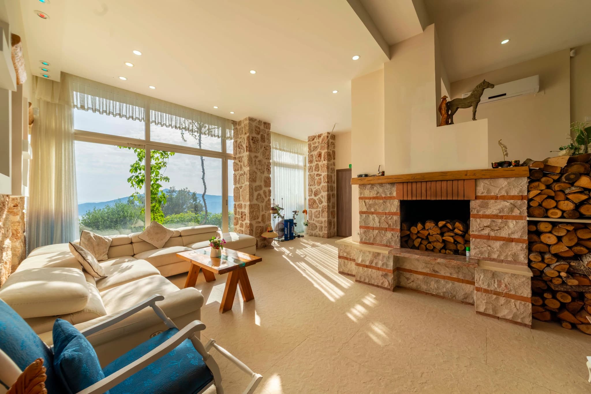 Modern living room with fireplace and sofa facing expansive windows with mountain views.