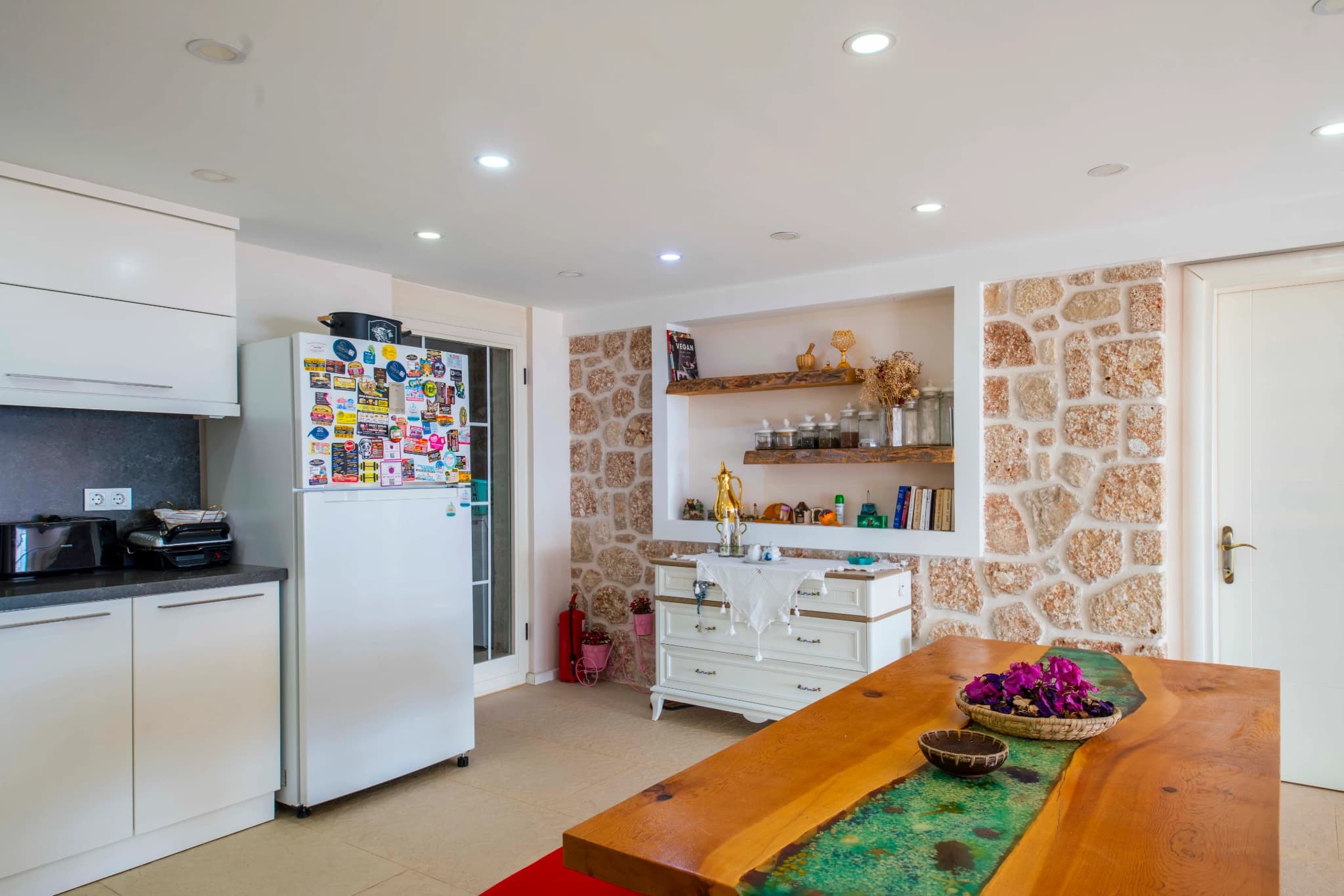 Modern kitchen with white cabinetry, open shelving, and integrated dining area.