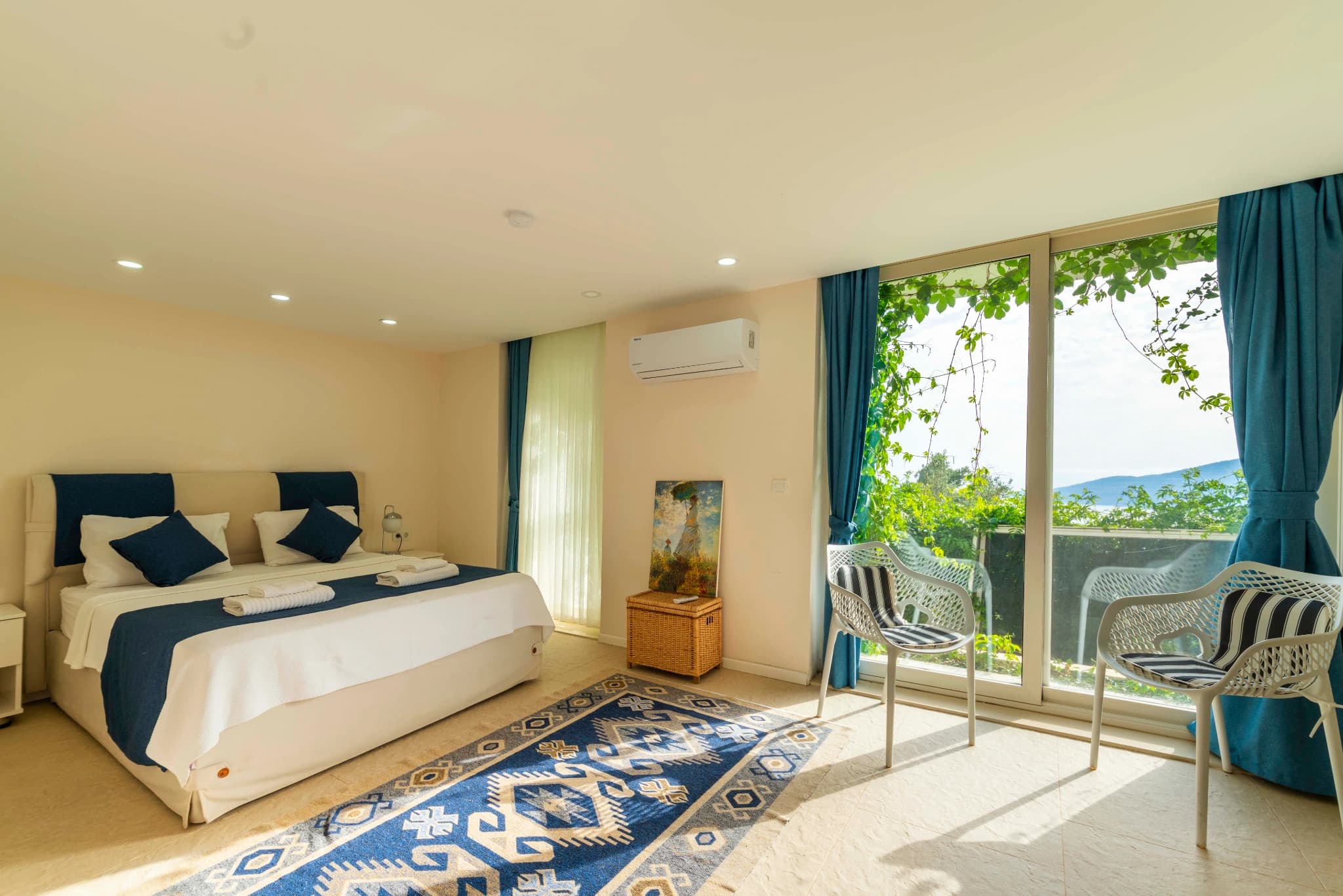 Bright bedroom with king bed, ensuite access, and private balcony overlooking mountains.