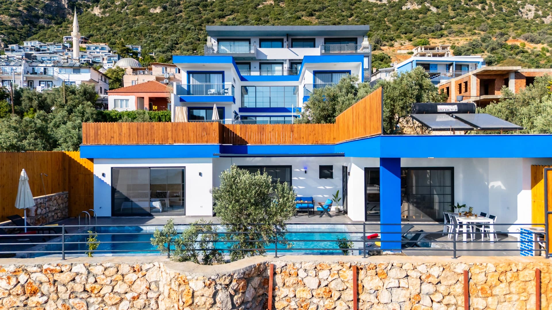 Modern blue and white villa with striking architectural design perched on a hillside.