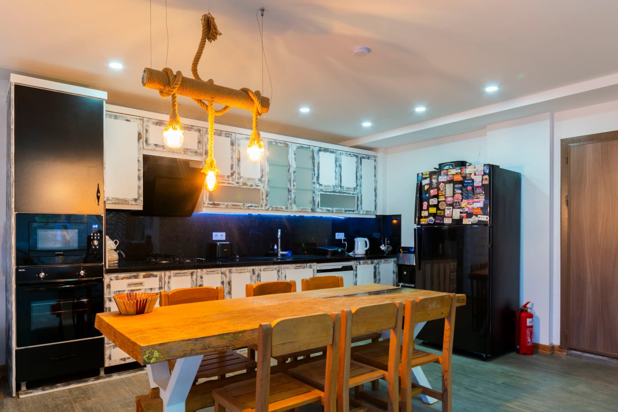 Modern kitchen with black countertops, dining area, and stylish pendant lighting.