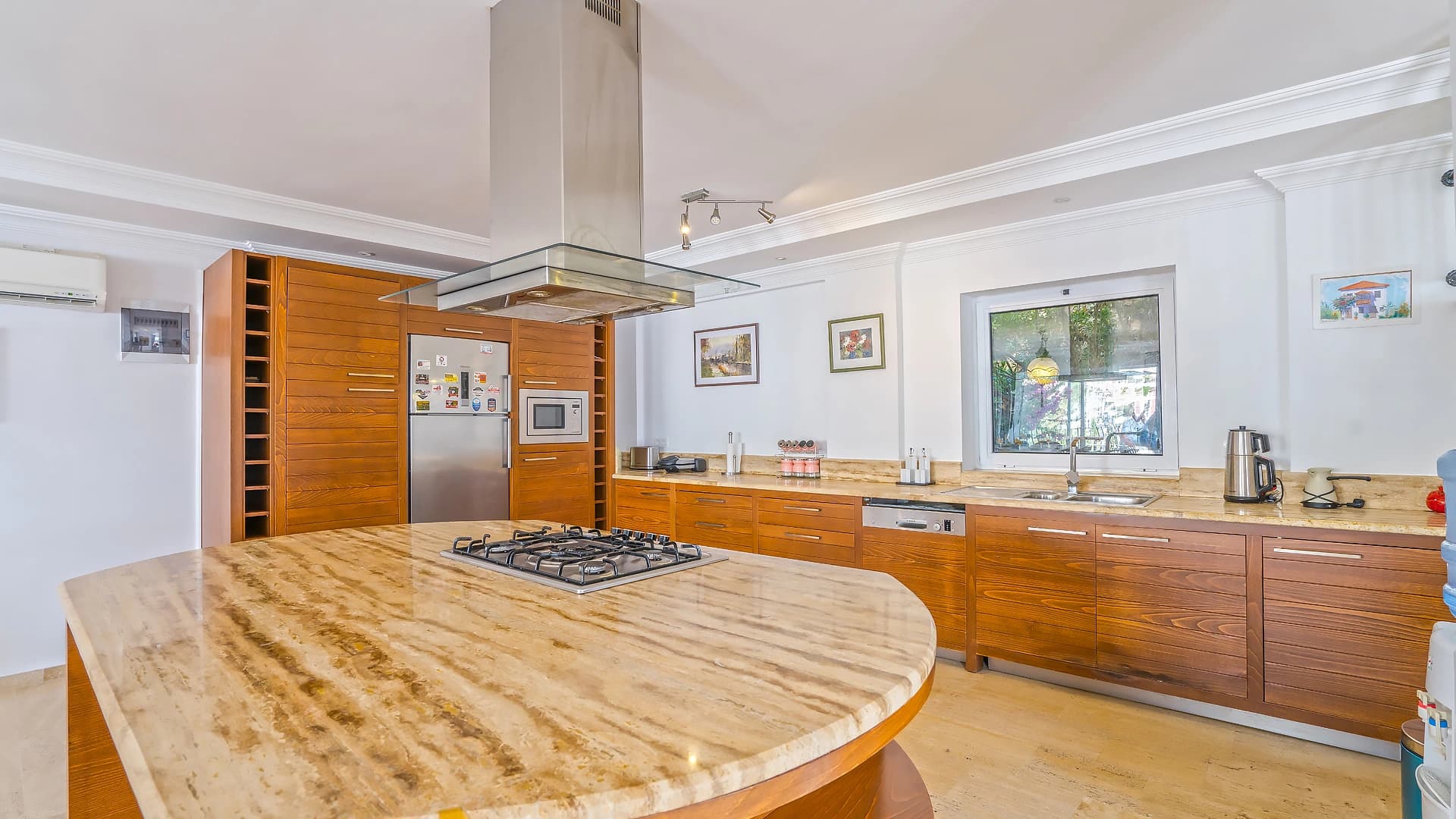 Modern kitchen with island, gas cooktop, and ample wooden cabinetry.