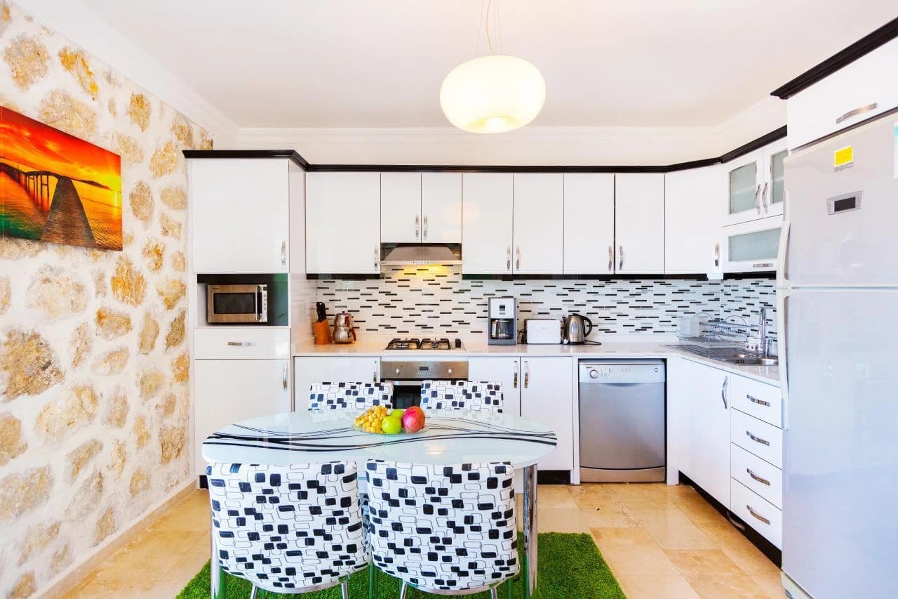 Well-equipped modern kitchen with island seating and mosaic tile backsplash.
