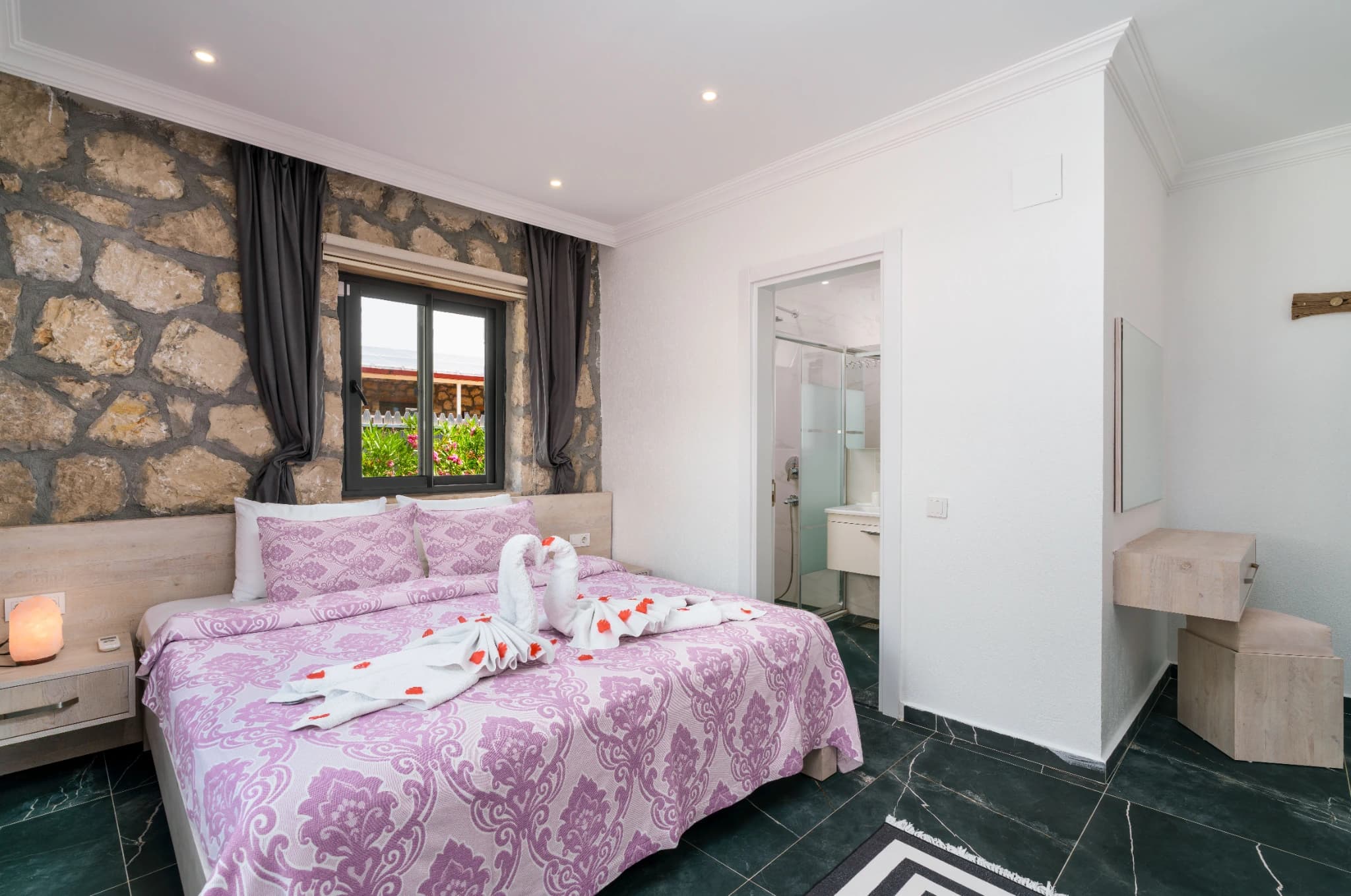 Bedroom with king bed, direct access to ensuite bathroom, and stone wall feature.