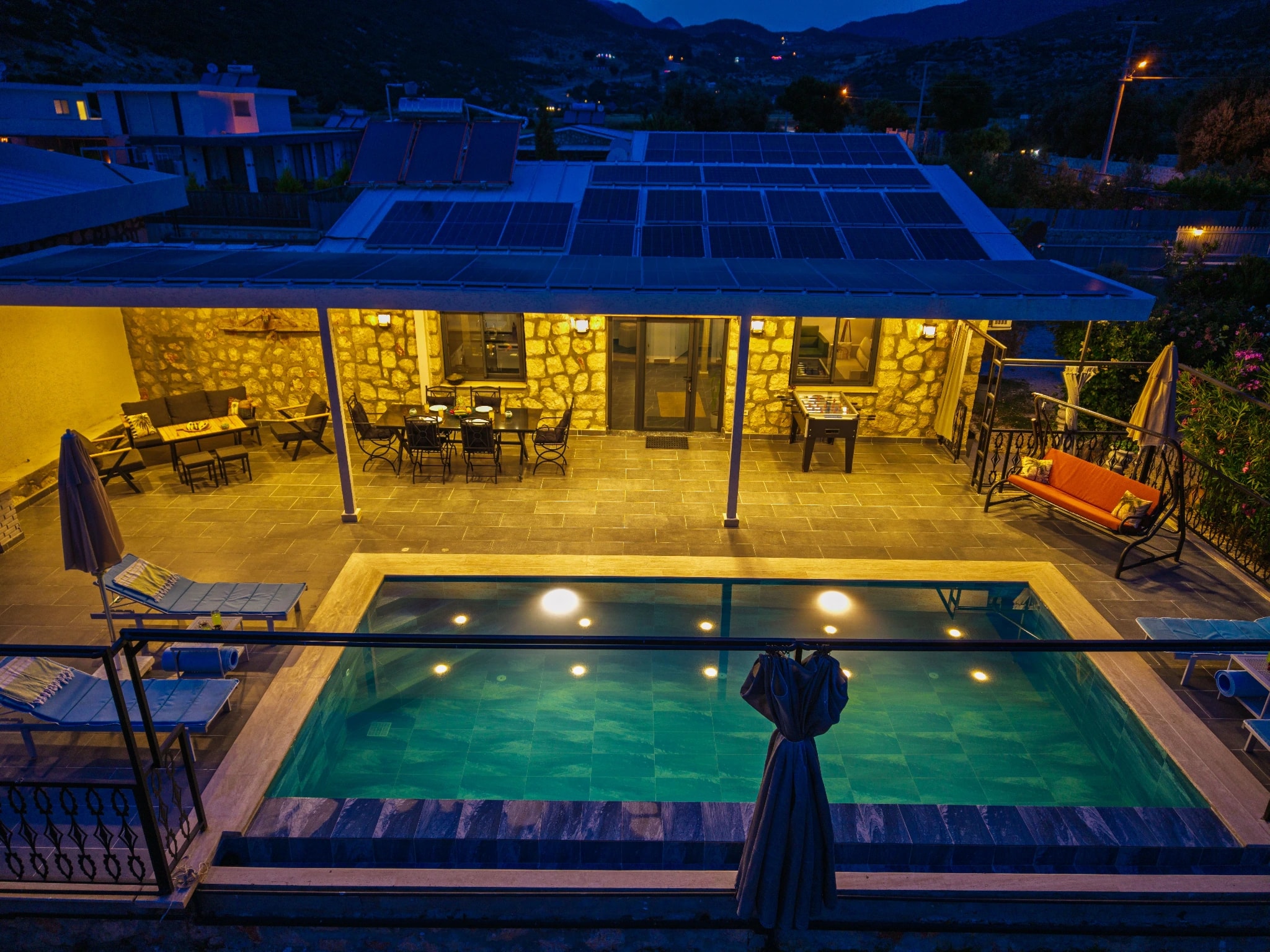 Spacious terrace with private pool, outdoor dining area, and mountain views at twilight.