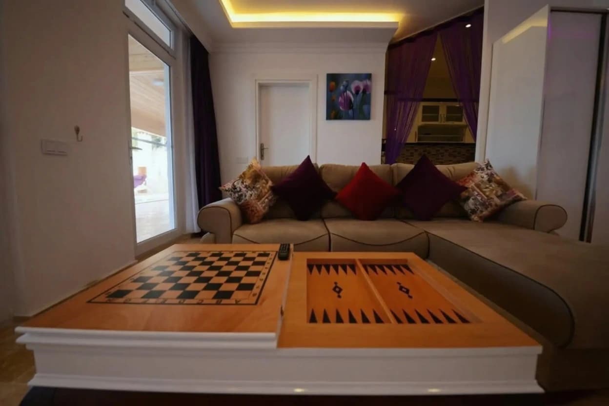 Modern living room with sectional sofa and built-in game tables for entertainment.