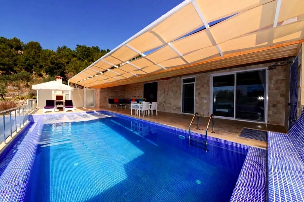 Resort-style pool with professional tiling, retractable shade, and panoramic landscape views.