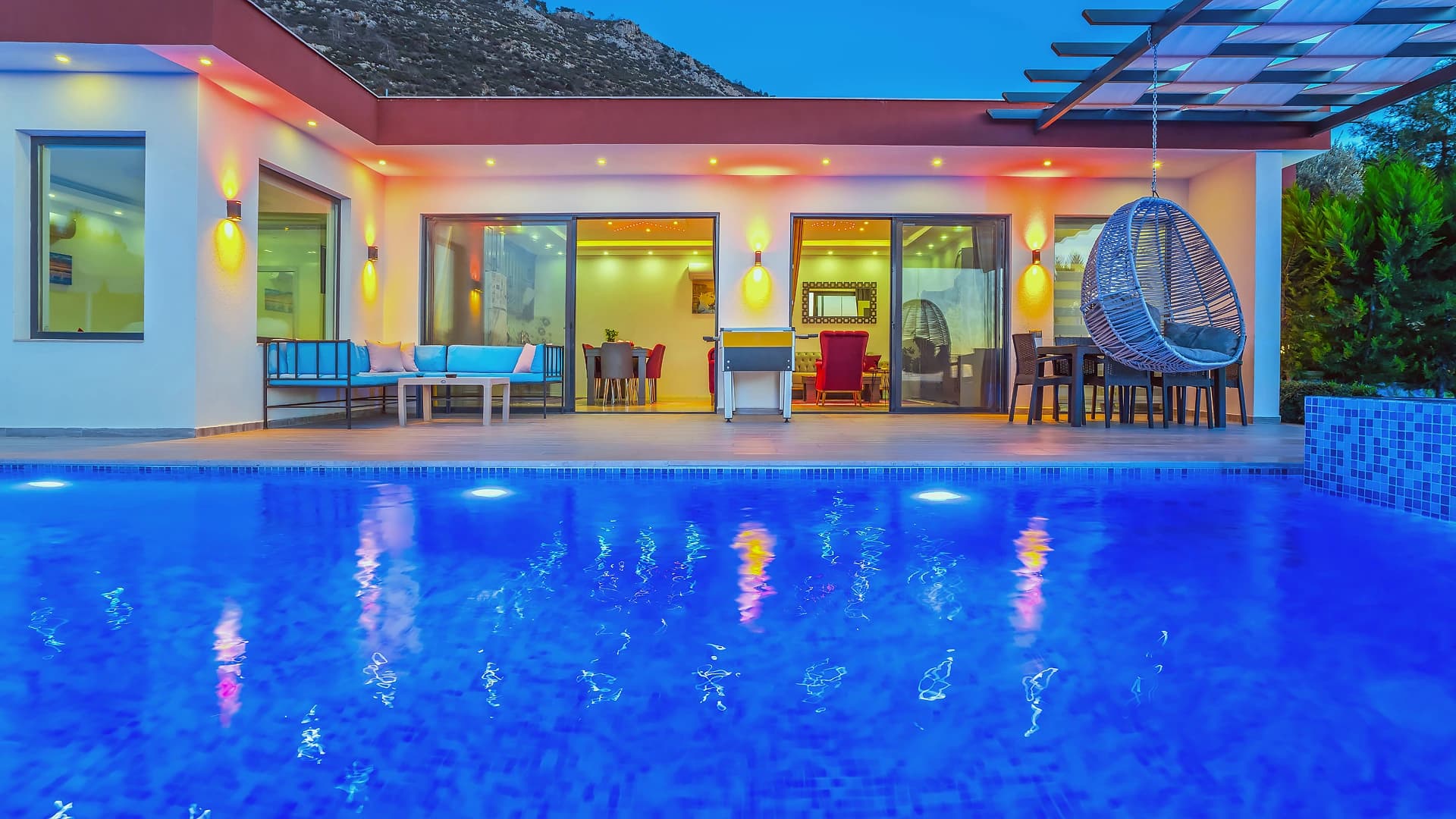 Expansive terrace with pool, dining area, hanging chair, and villa interior access.