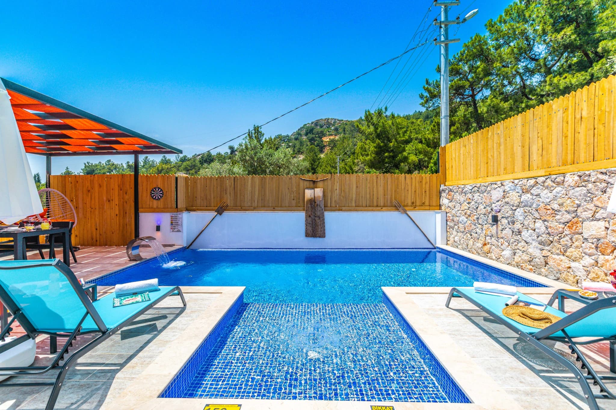 Striking pool view with mountain backdrop and shaded pergola area.