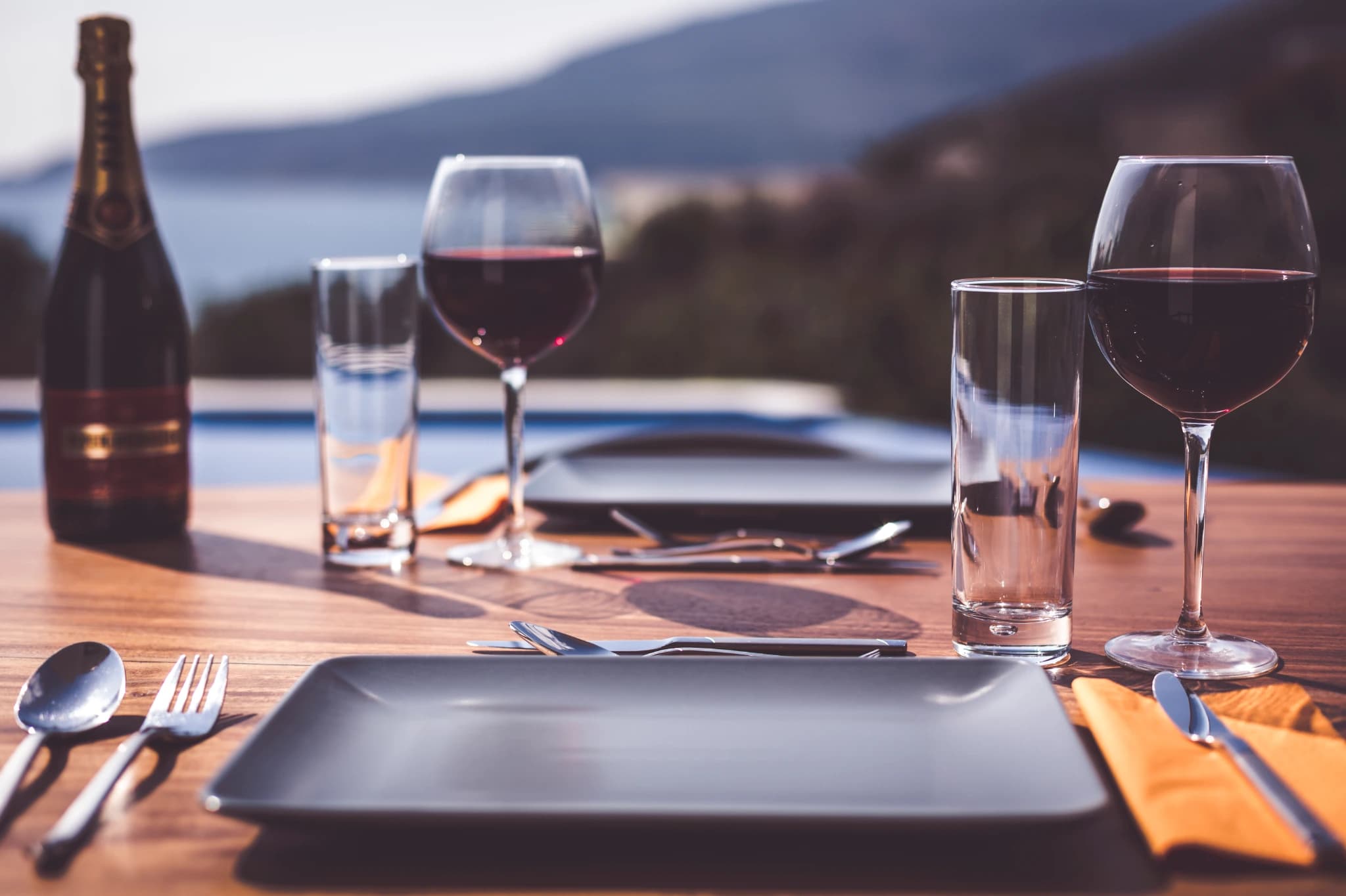 Fine dining table set with wine overlooking scenic lake and mountains.