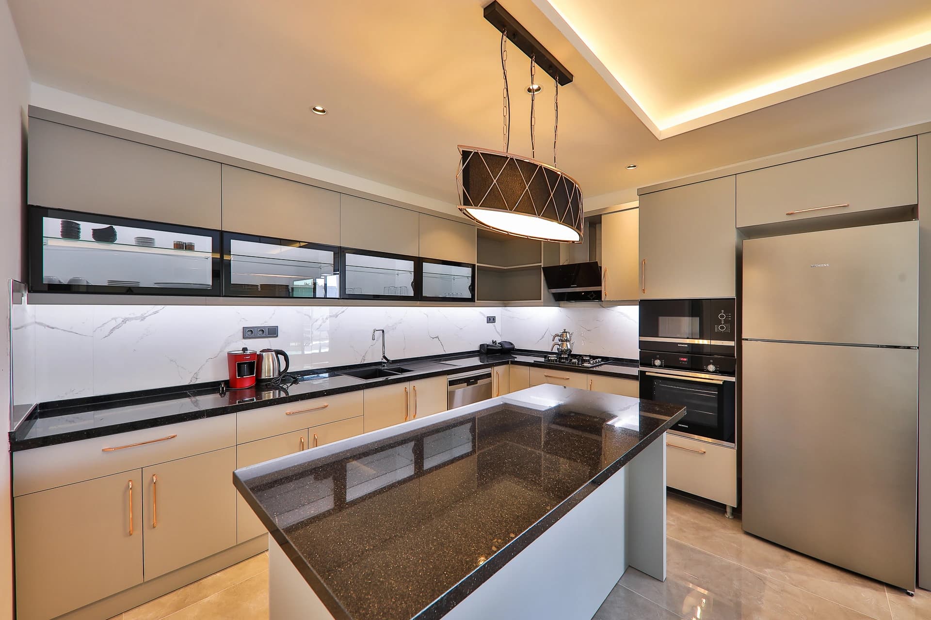 Modern kitchen with large island, gas cooktop, and pendant lighting.