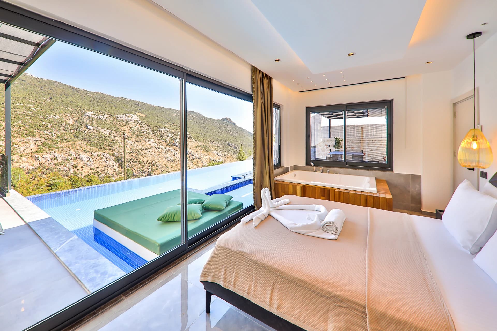 Spacious second bedroom with twin beds, ensuite bathroom with soaking tub, and panoramic mountain and pool vistas.