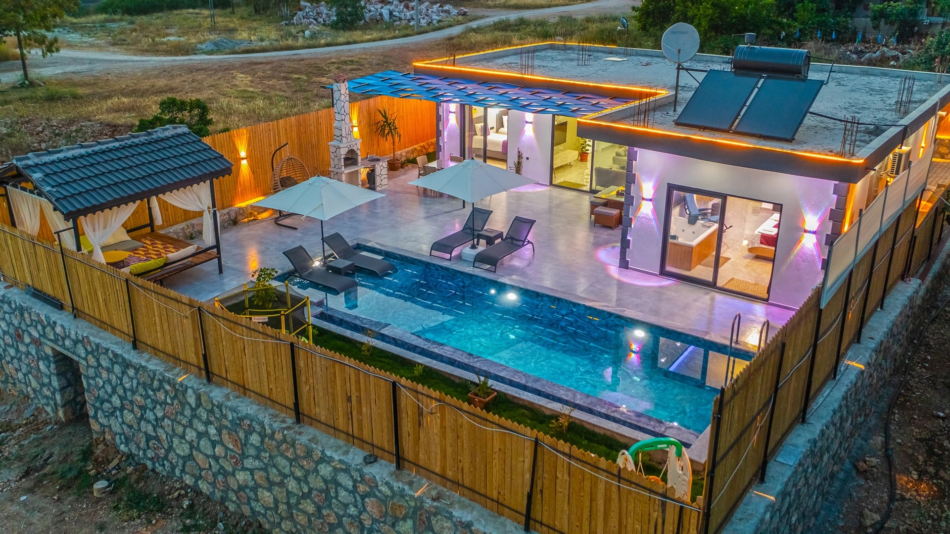 Full property aerial view at dusk showing villa, pool deck, and surrounding landscape.