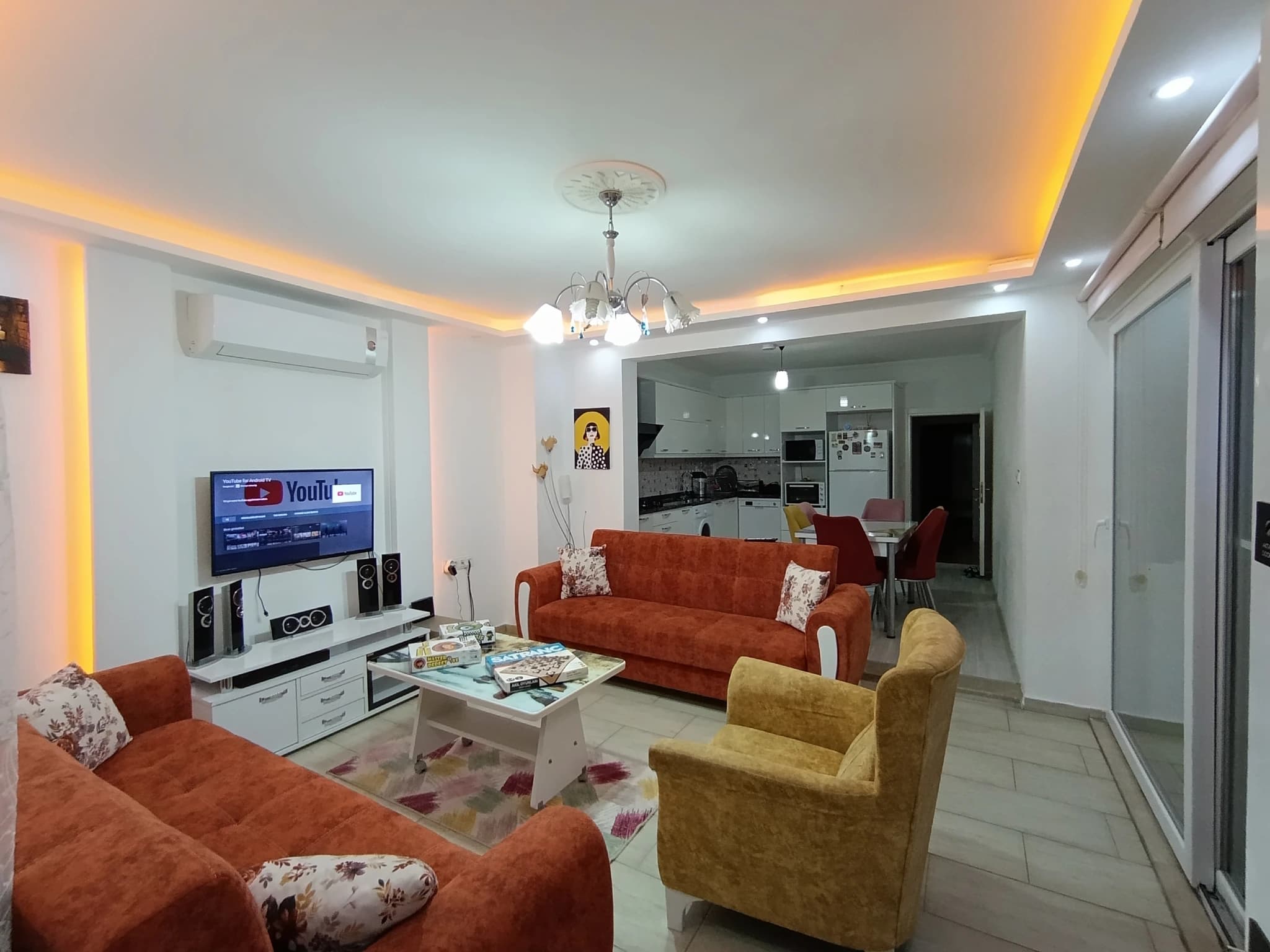 Geschützte Villa mit Naturblick, Privatpool und Garten in Kalkan – Spacious open-plan living room with orange sofas, ambient ceiling lighting, and access to kitchen.