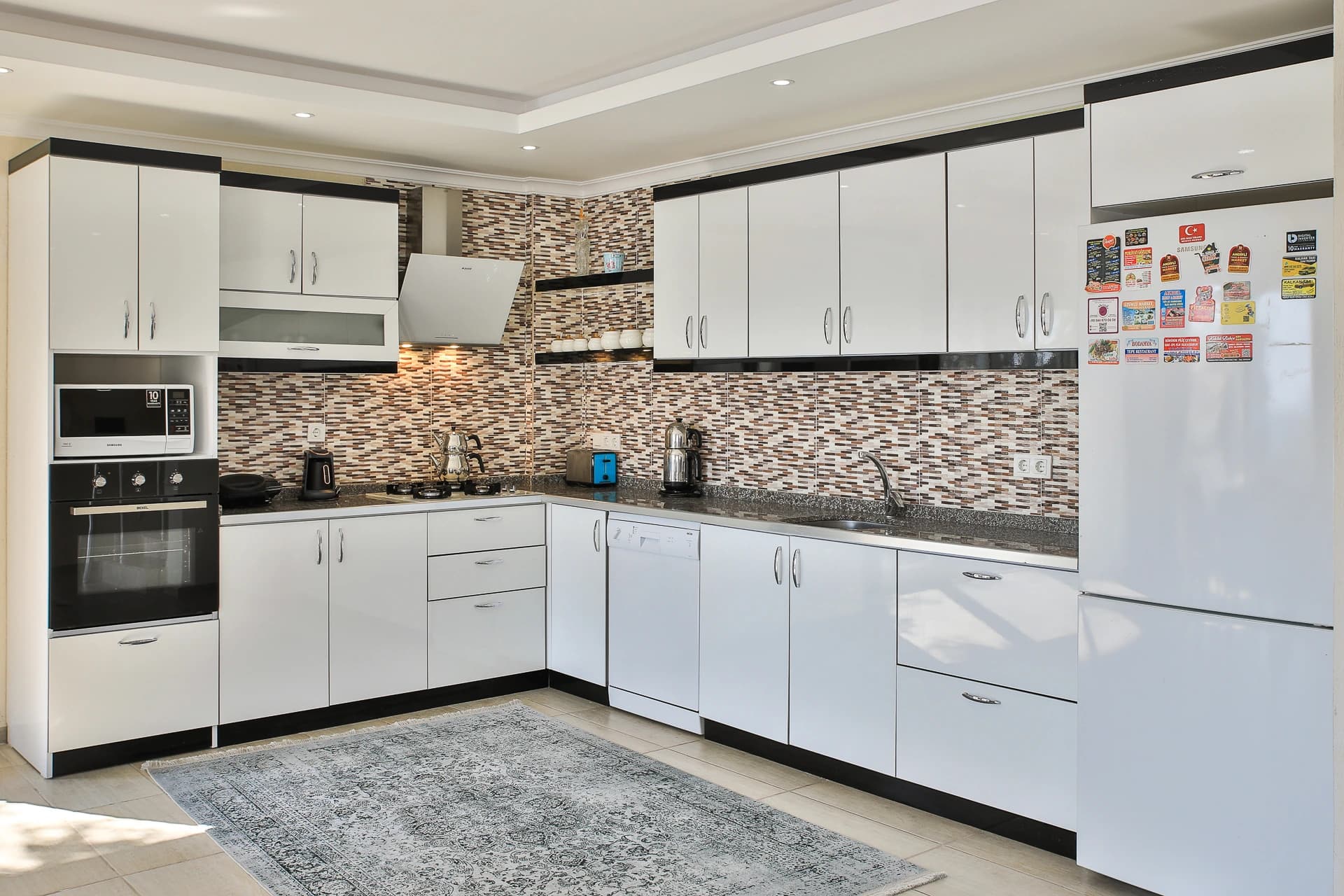 Modern kitchen with white cabinets, tiled backsplash, and built-in appliances.
