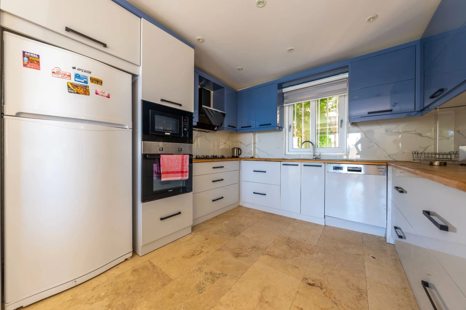 Spacious kitchen view showing appliances and continued blue and white cabinetry design.