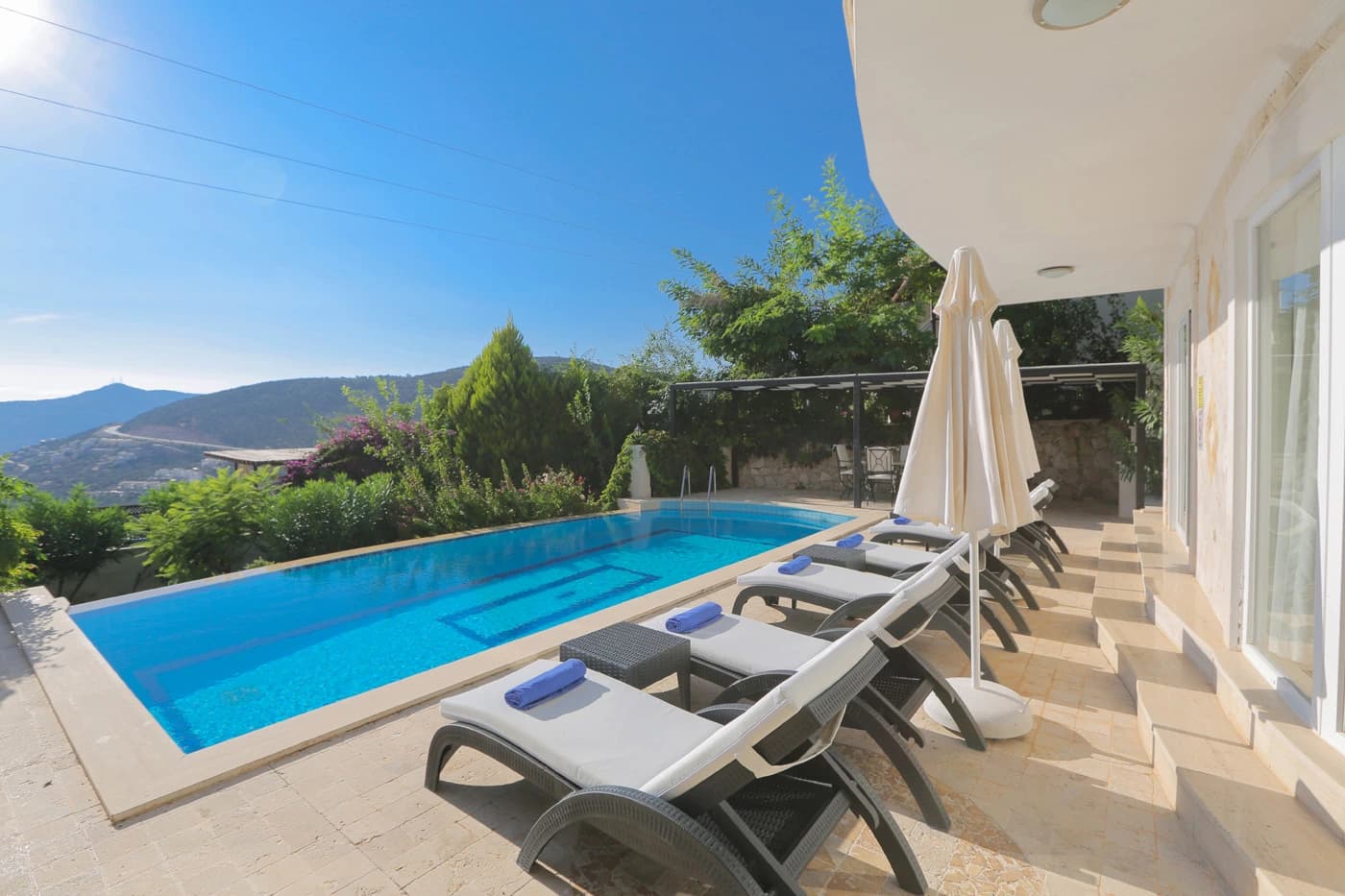 Private swimming pool with mountain views, sun loungers, and professional umbrellas.
