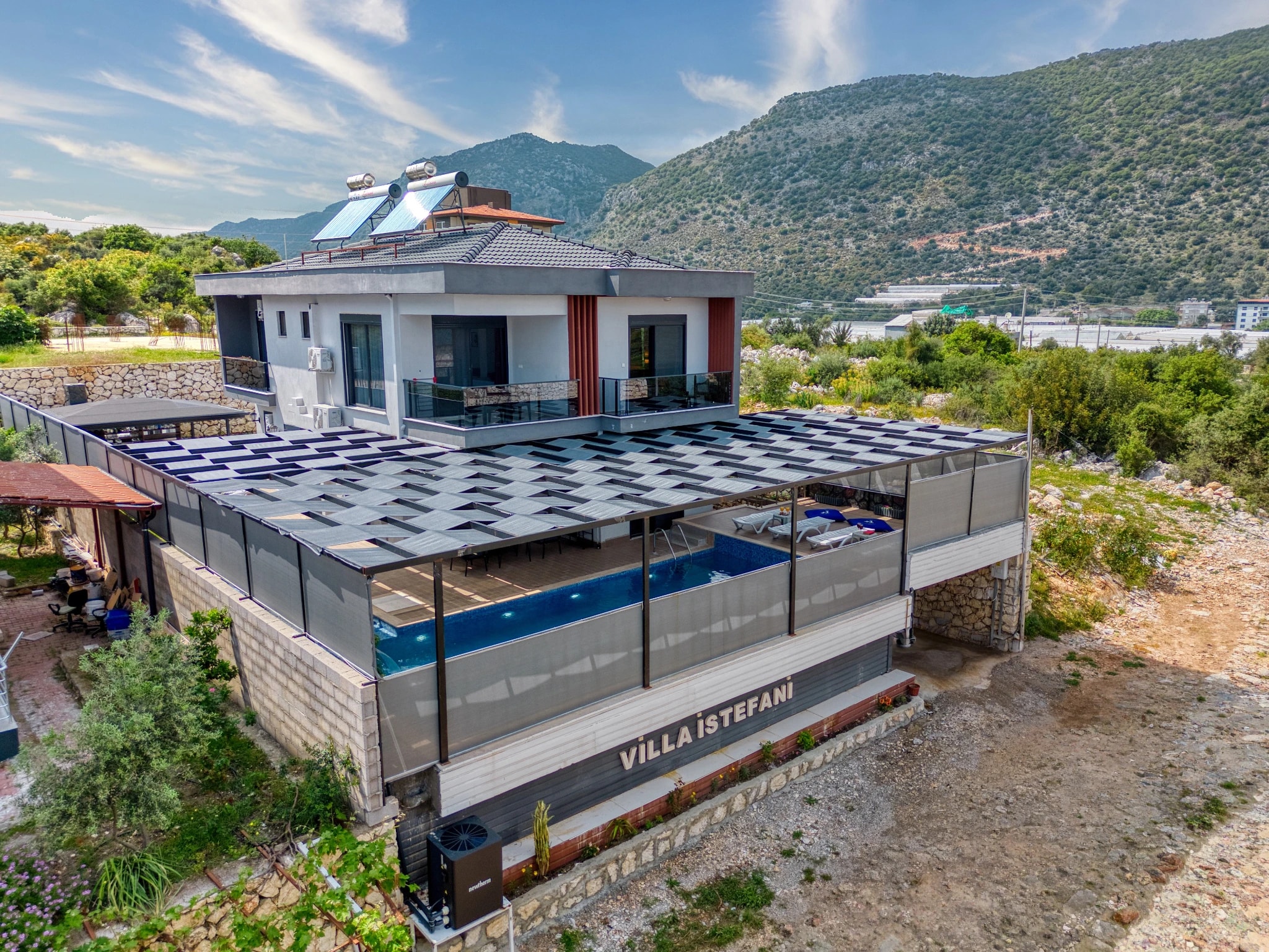 Aerial view of villa with private pool, mountain scenery, and contemporary architectural design in natural landscape.